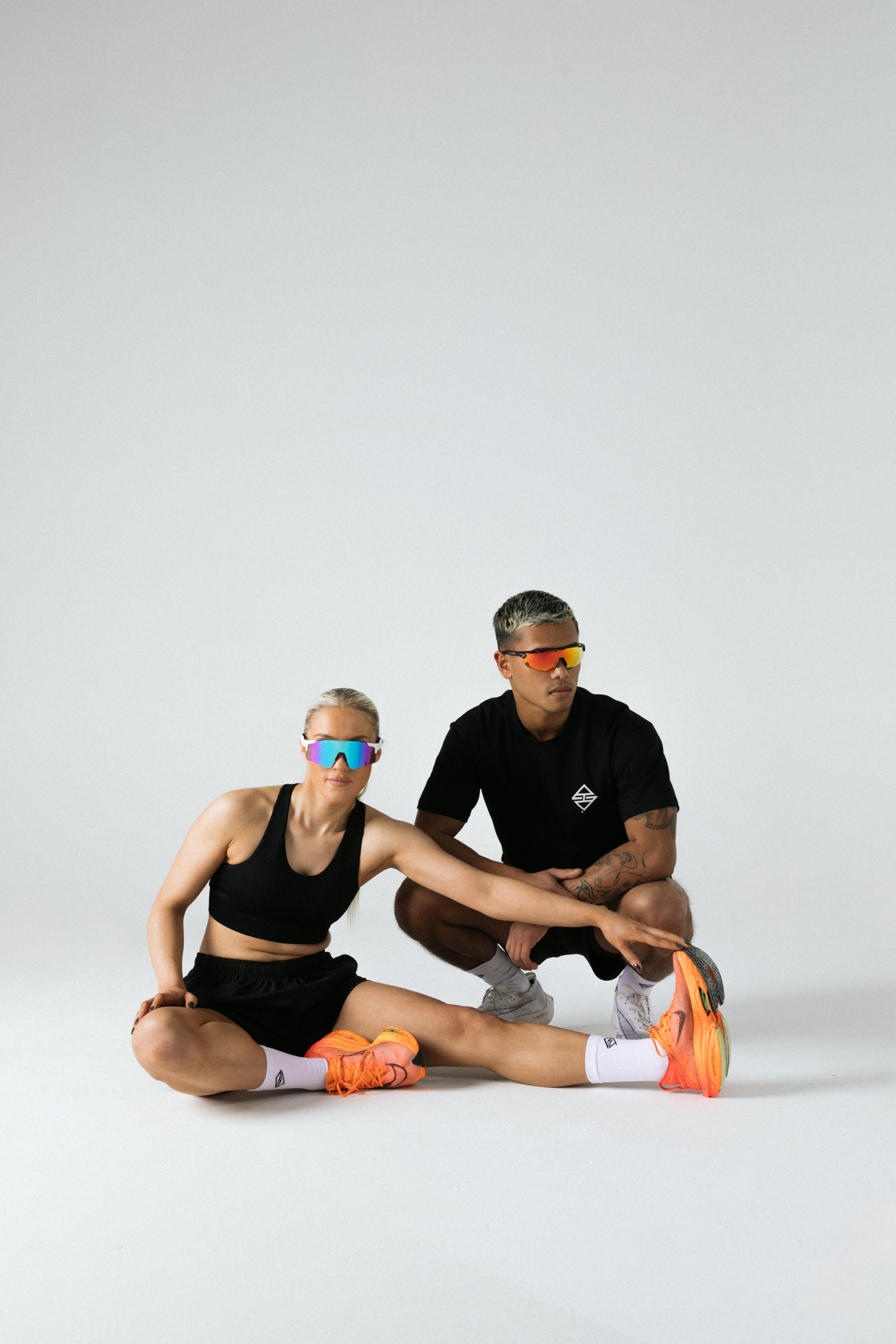 Dynamic duo in matching sunglasses promoting a vibrant fitness event at Honey Street Studio.