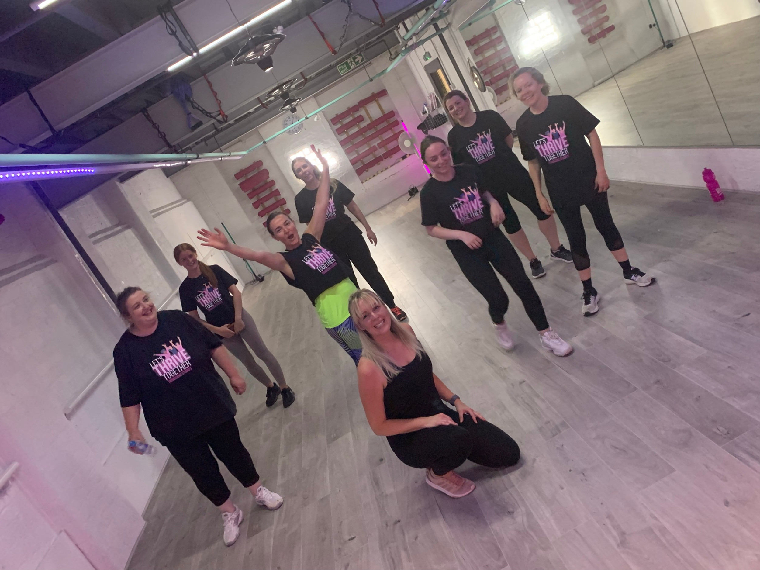 Vibrant fitness group in matching t-shirts at Transcend Tribe coaching center event.
