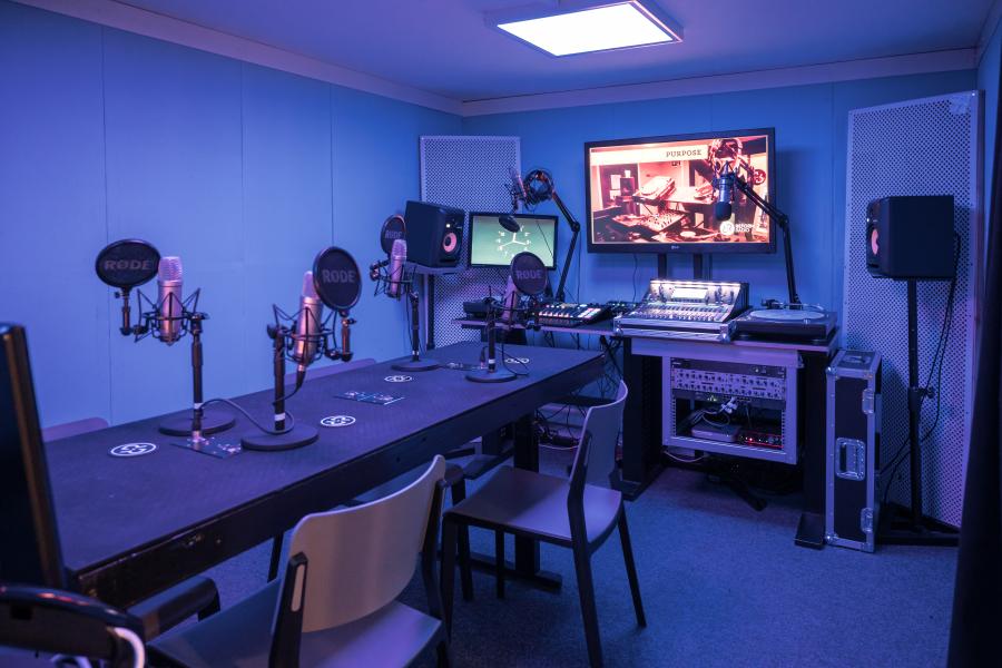 Modern rehearsal space with microphones and large screen for events and meetings.