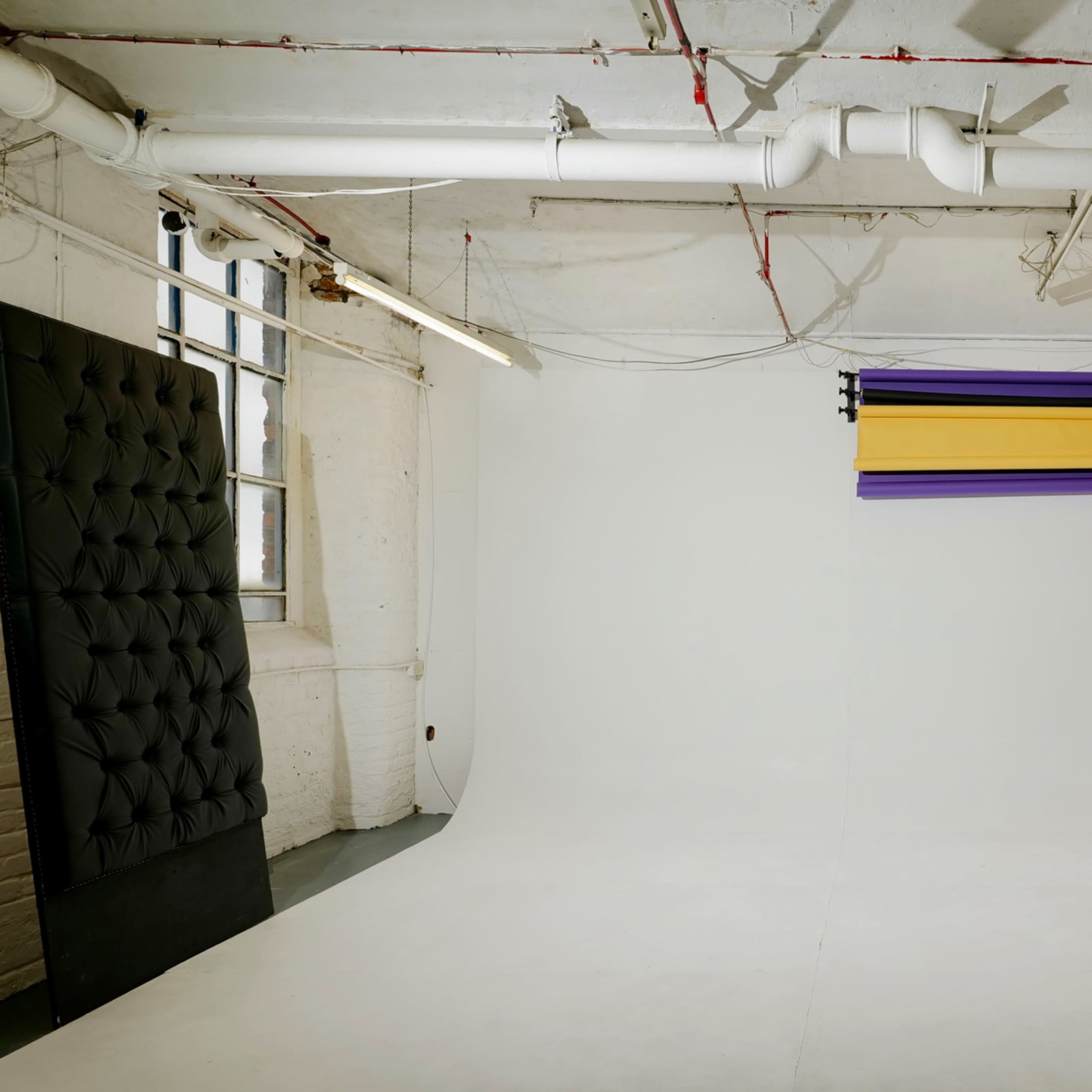Minimalist photography studio with colorful paper rolls for versatile events and workshops.