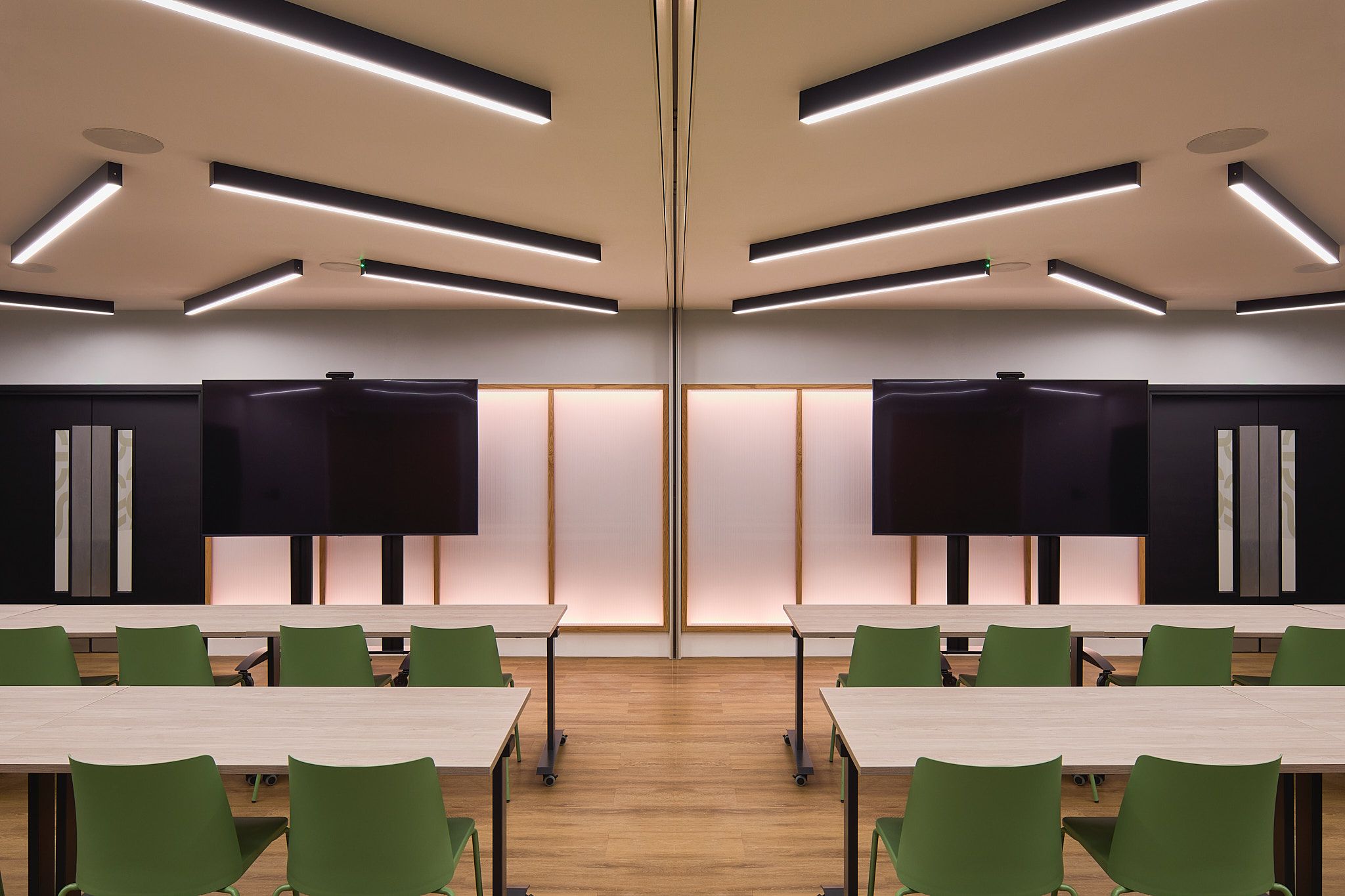 Modern auditorium in HubHub - Worship Square for workshops, featuring green chairs and dual screens.