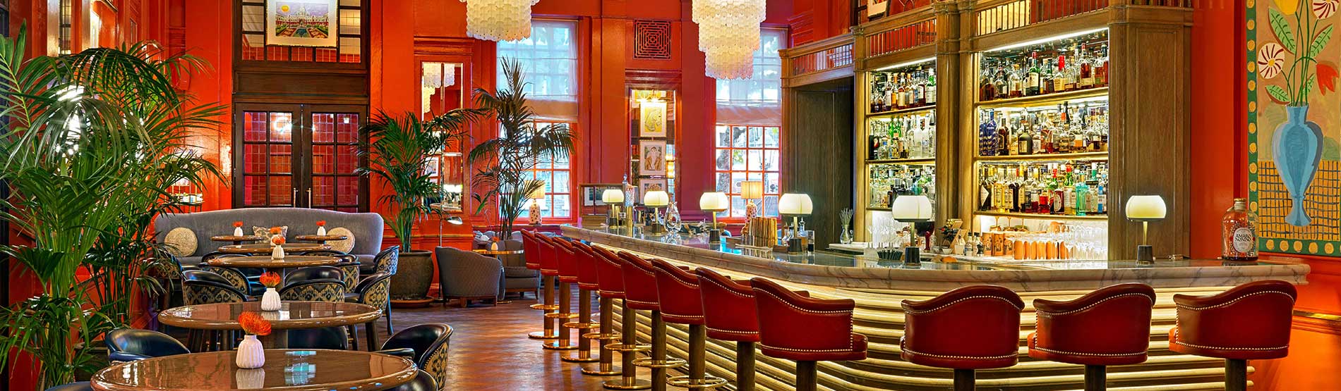 Stylish cocktail bar at The Coral Room with rich red walls for networking events.