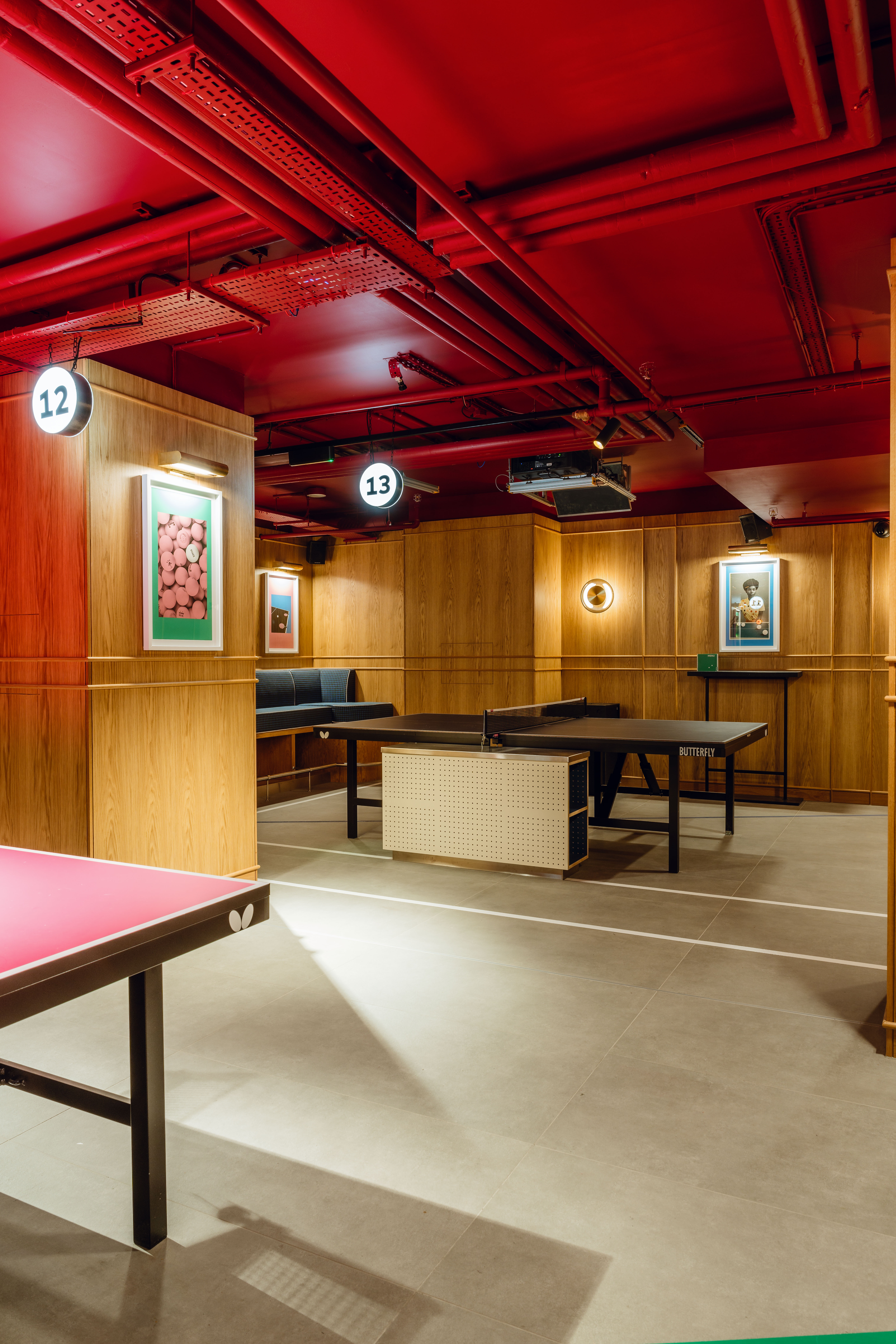 Versatile meeting space with wood paneling and ping pong tables for corporate events.