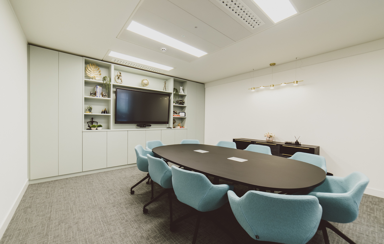 Modern meeting room in Arkwright House with sleek oval table and blue chairs.