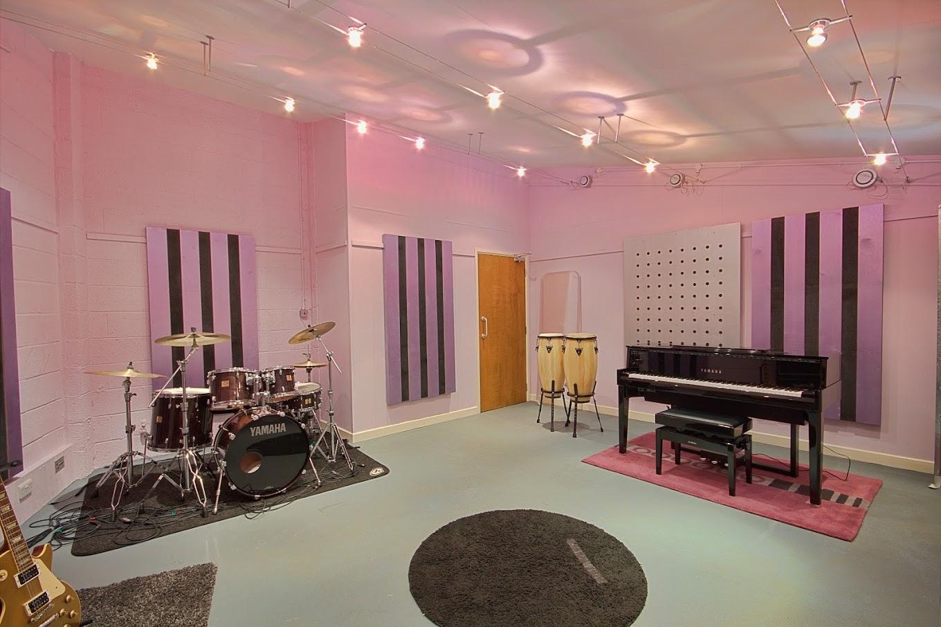 Vibrant music studio with drum set and pink walls, perfect for creative events.