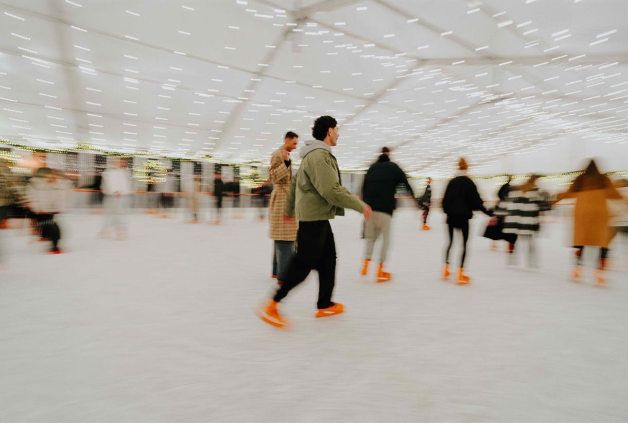 Winter Assembly ice skating event with twinkling lights and lively skaters in winter attire.
