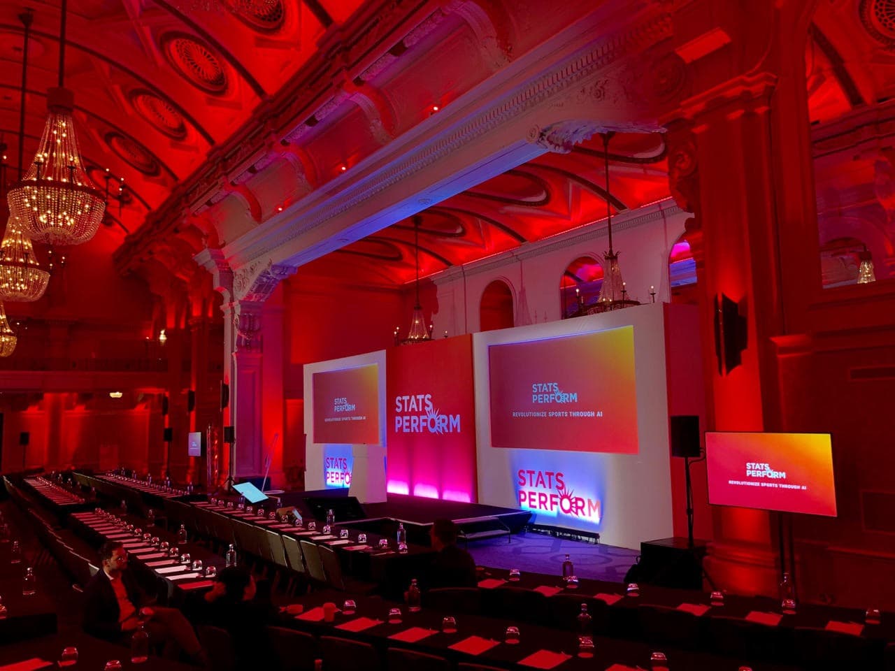 Corporate event setup in Grand Connaught Rooms with LED lighting and long-table configuration.