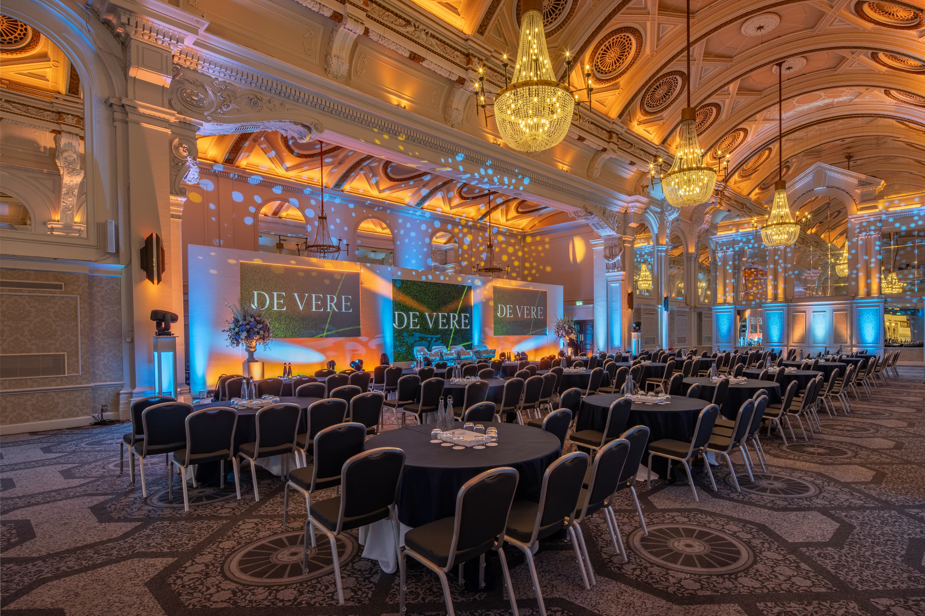 Grand Connaught Rooms gala ballroom, elegant dinner setup with projection screens, event venue.