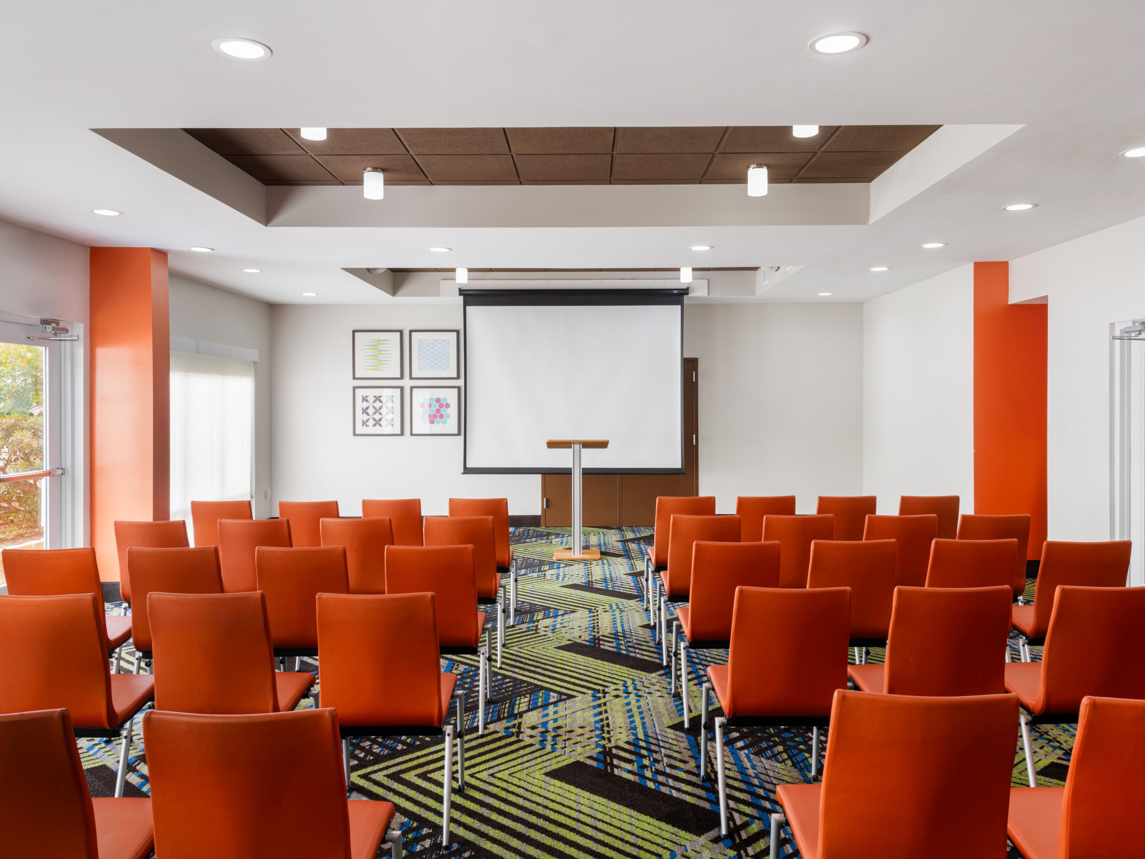 Modern event hall with orange chairs, perfect for seminars and workshops.