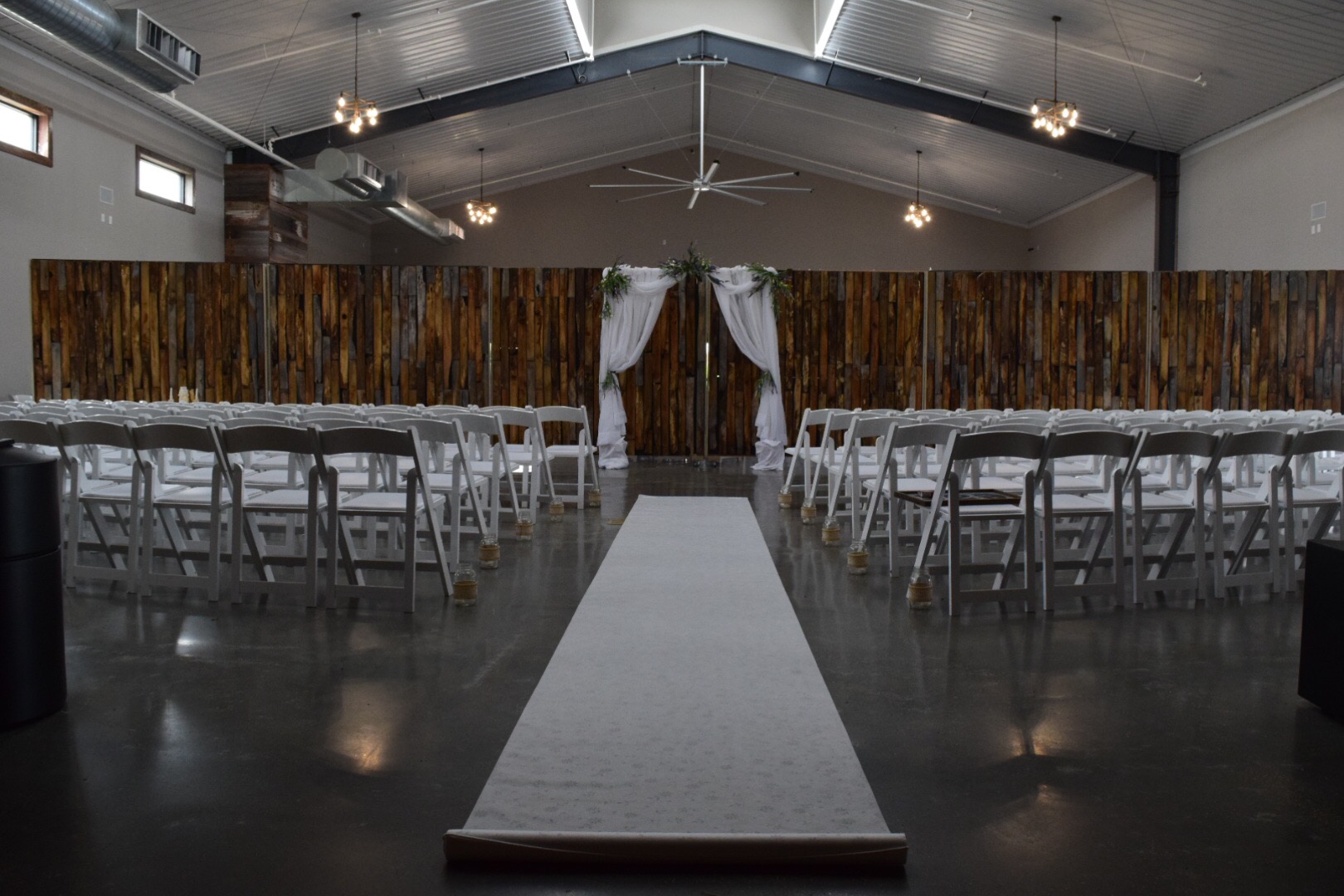Spring Hill Event Hall: Rustic industrial wedding venue, white chairs, draped arch.