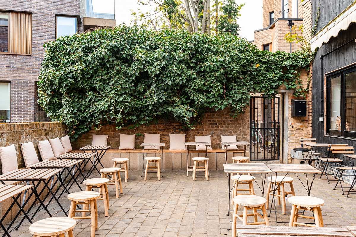 Rustic-chic restaurant outdoor event space, ivy backdrop, small gatherings