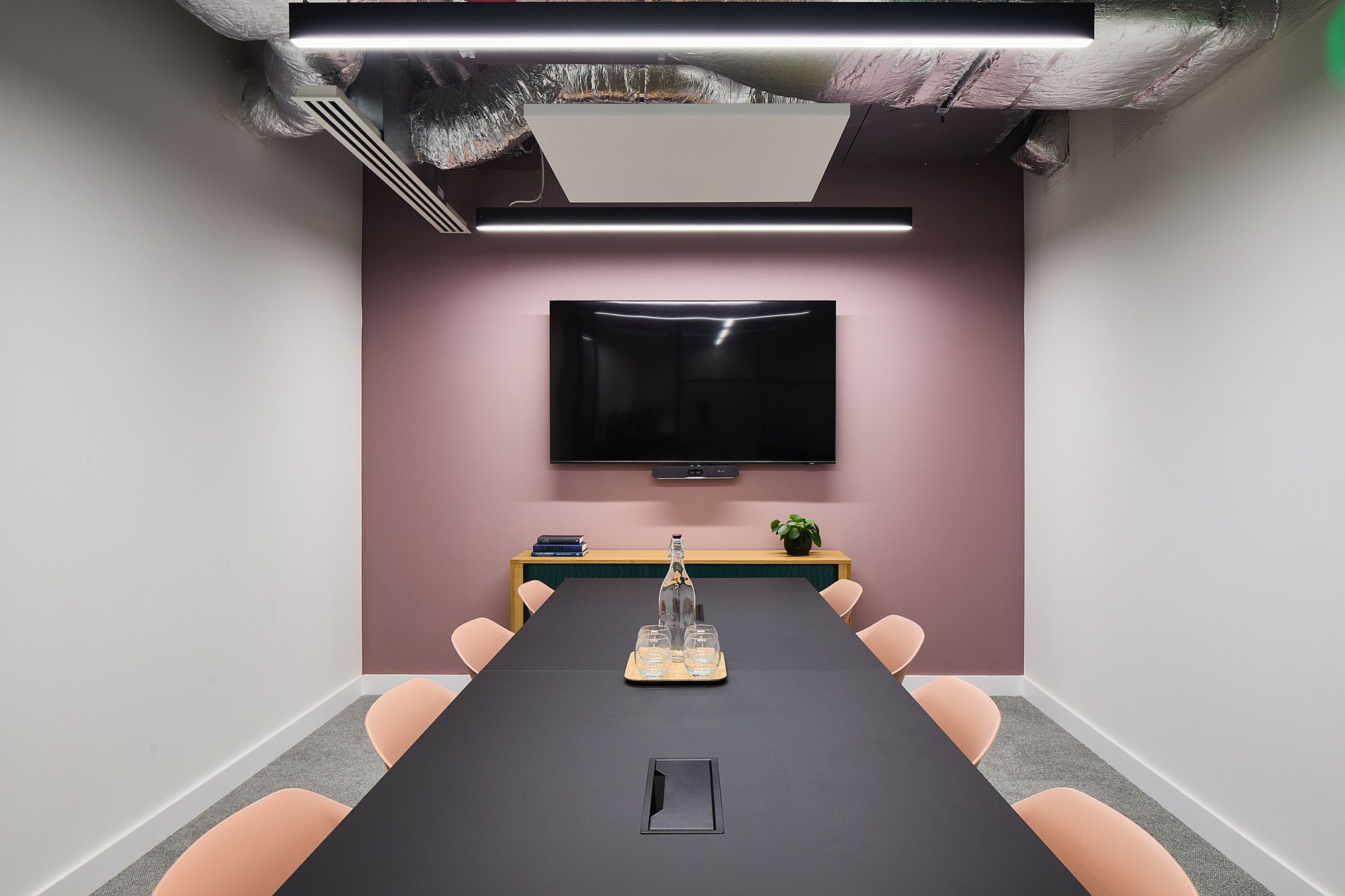 Modern Hoxton meeting room with sleek table and pink chairs, perfect for professional gatherings.