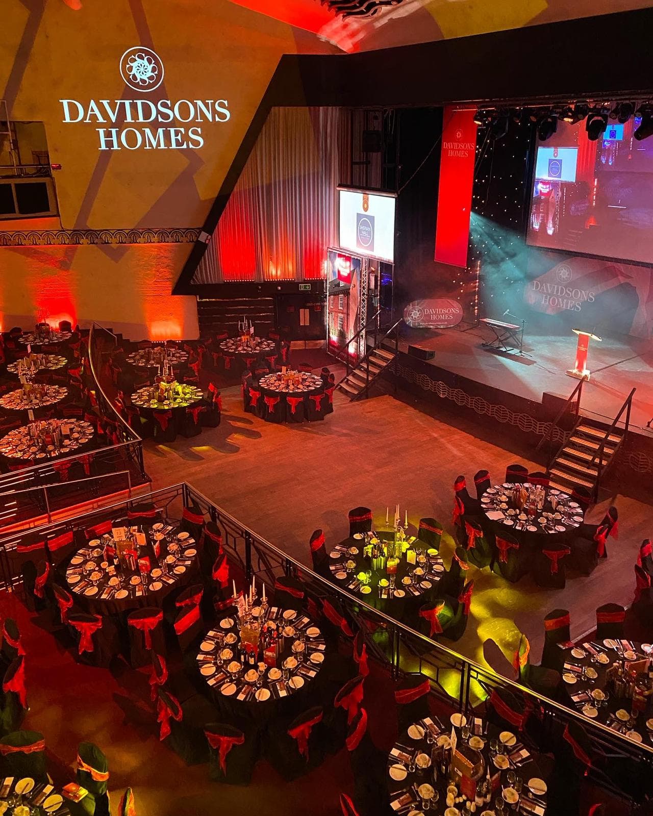 Vibrant event space in Athena with red-accented tables for awards ceremony.