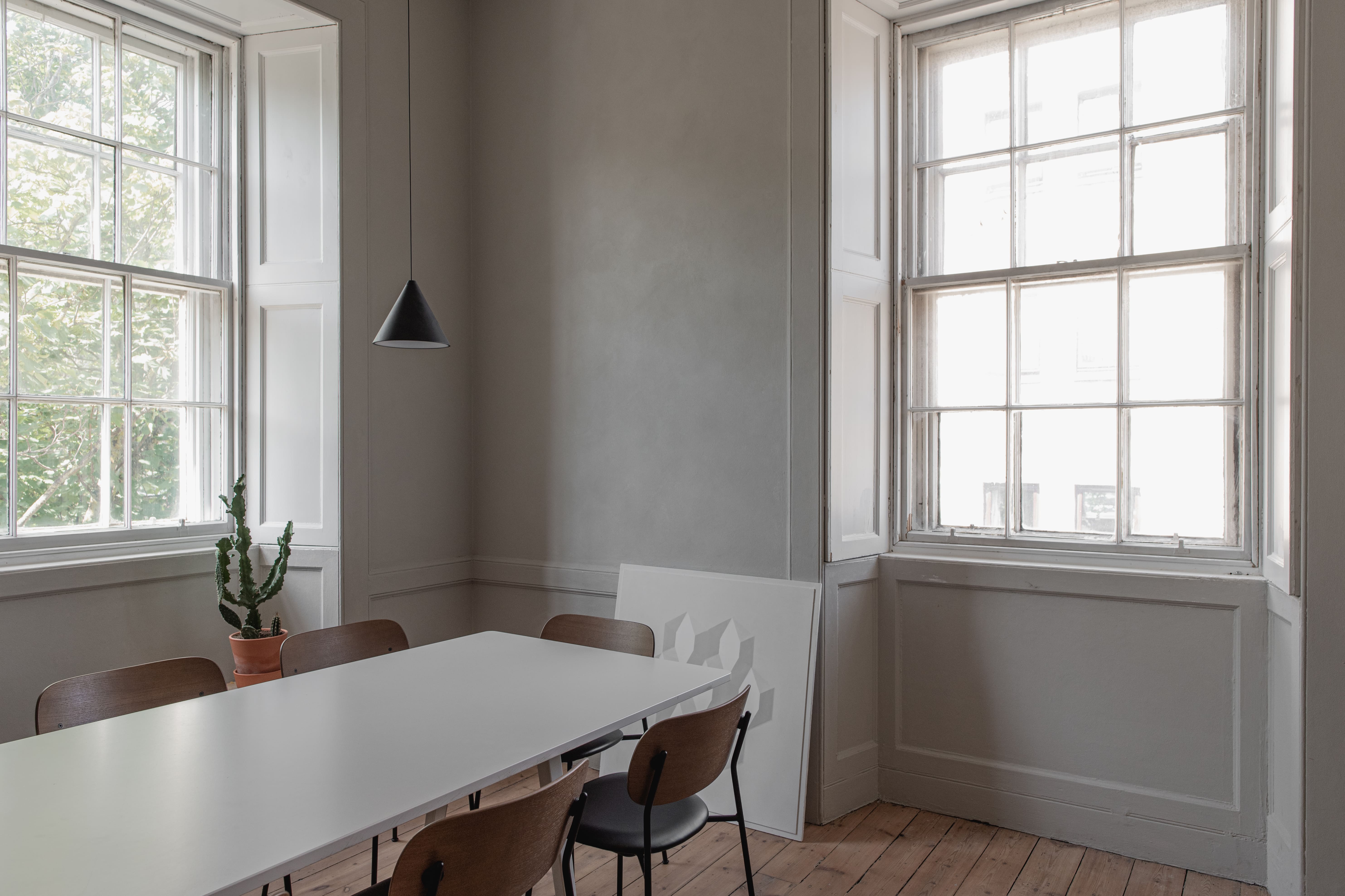 Modern minimalist meeting room with natural light, ideal for small team gatherings.