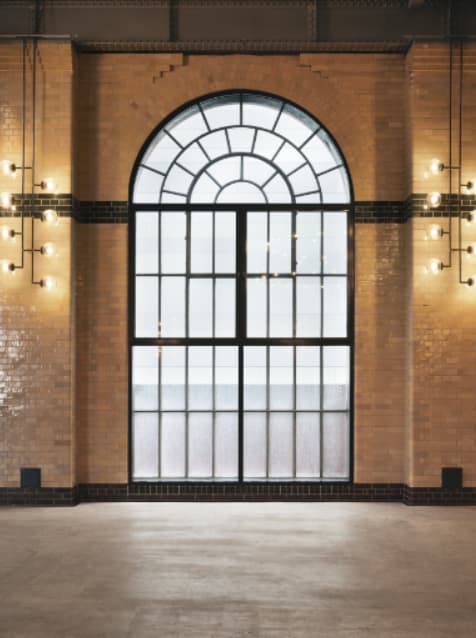 Industrial-chic exhibition space with arched windows for brand activation and event photography.