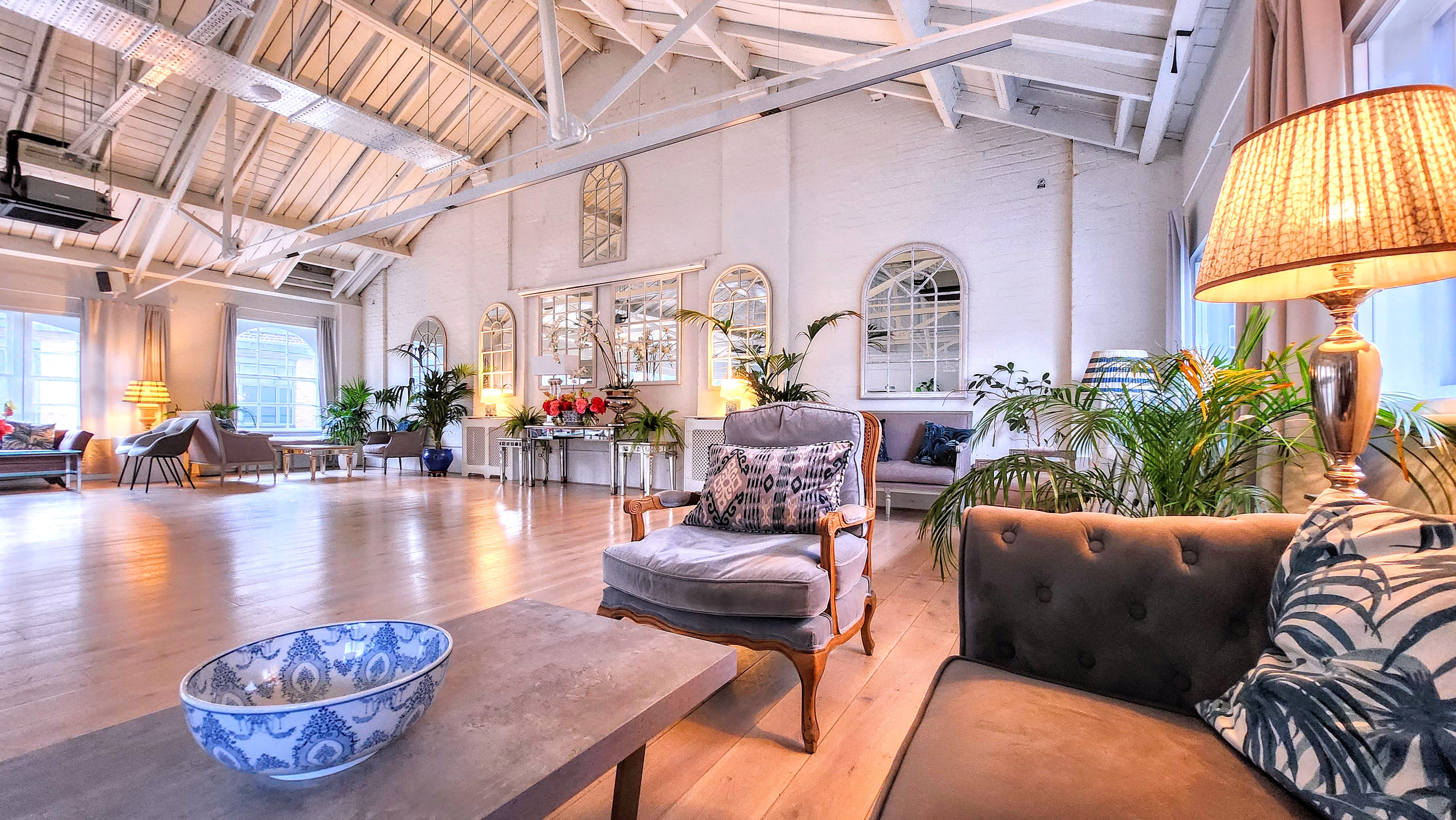 Stylish event venue with high ceilings and greenery for networking or gatherings.