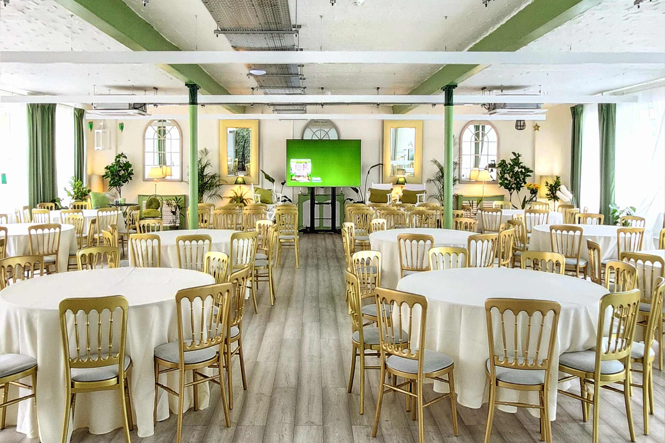 Elegant event space with round tables and gold chairs, perfect for corporate meetings or gatherings.