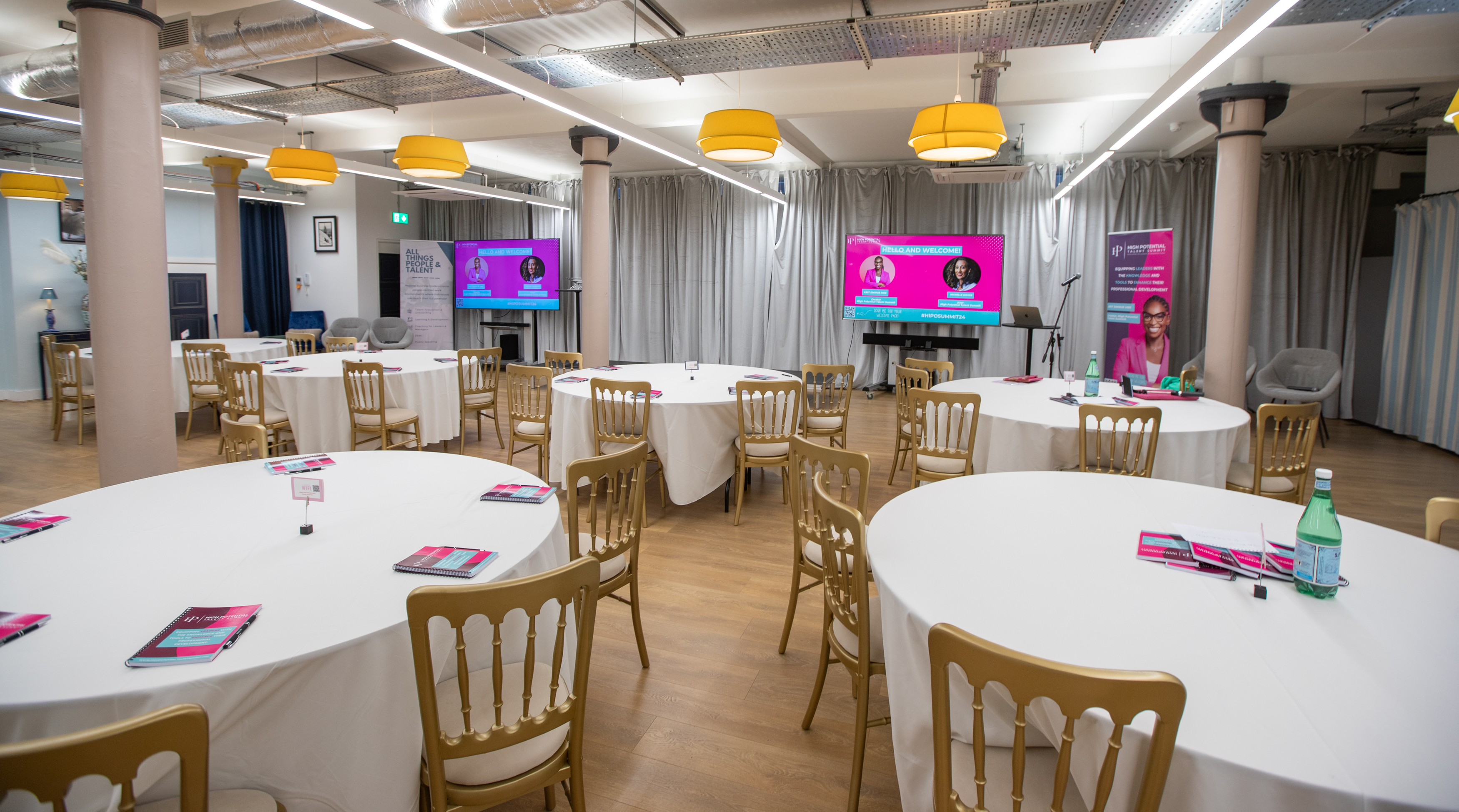 Event space with round tables, gold chairs, ideal for networking and workshops.