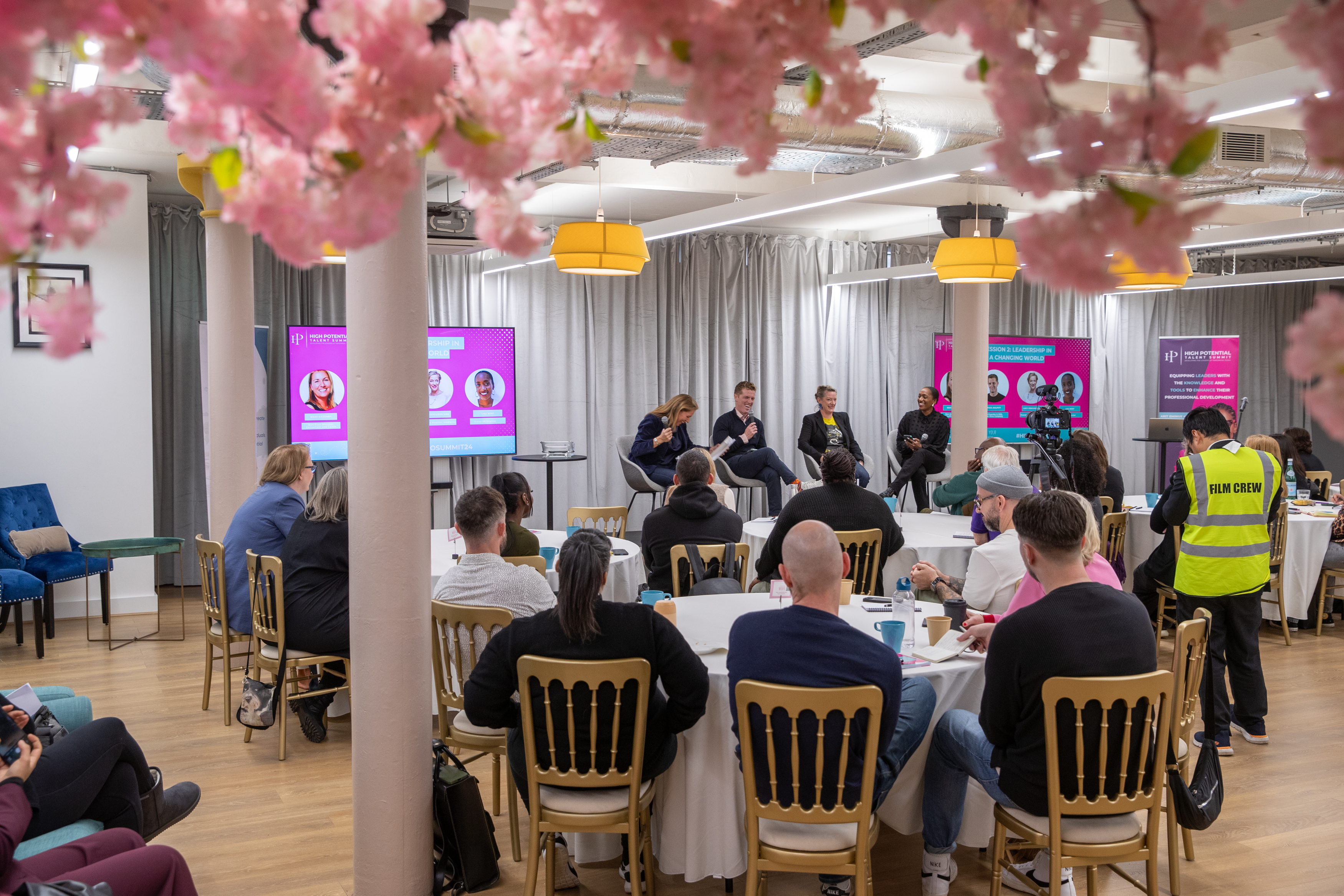 Event space with panel discussion, cherry blossom decor, networking opportunity.