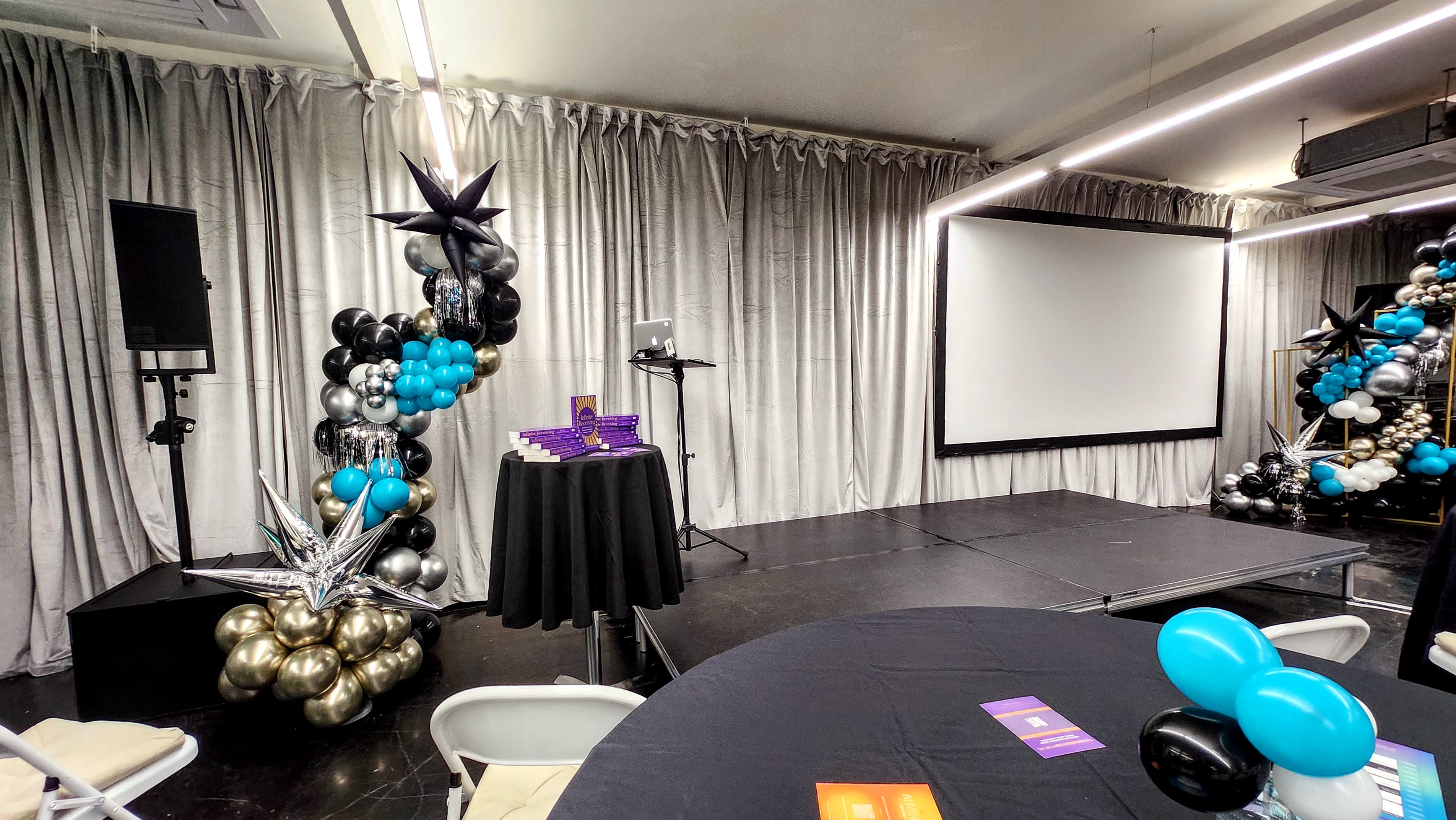 Event space at La Galeria with stage, balloons for presentations and celebrations.
