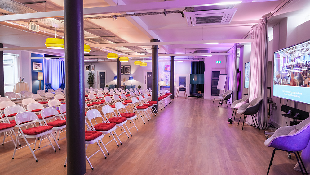 Event space with white chairs and red cushions, perfect for presentations and seminars.