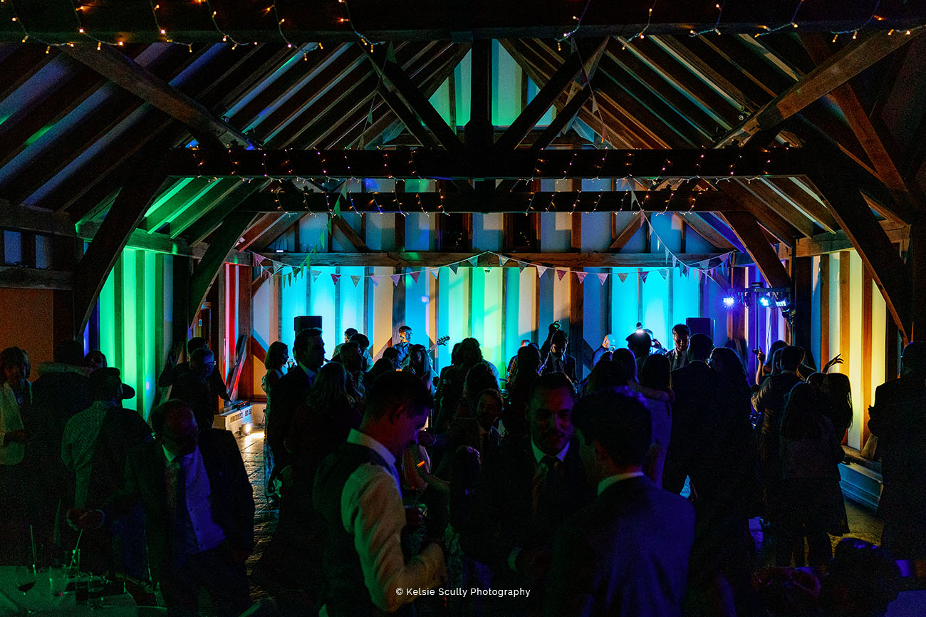 Vibrant Brookfield Barn event space with guests mingling under colorful lights.
