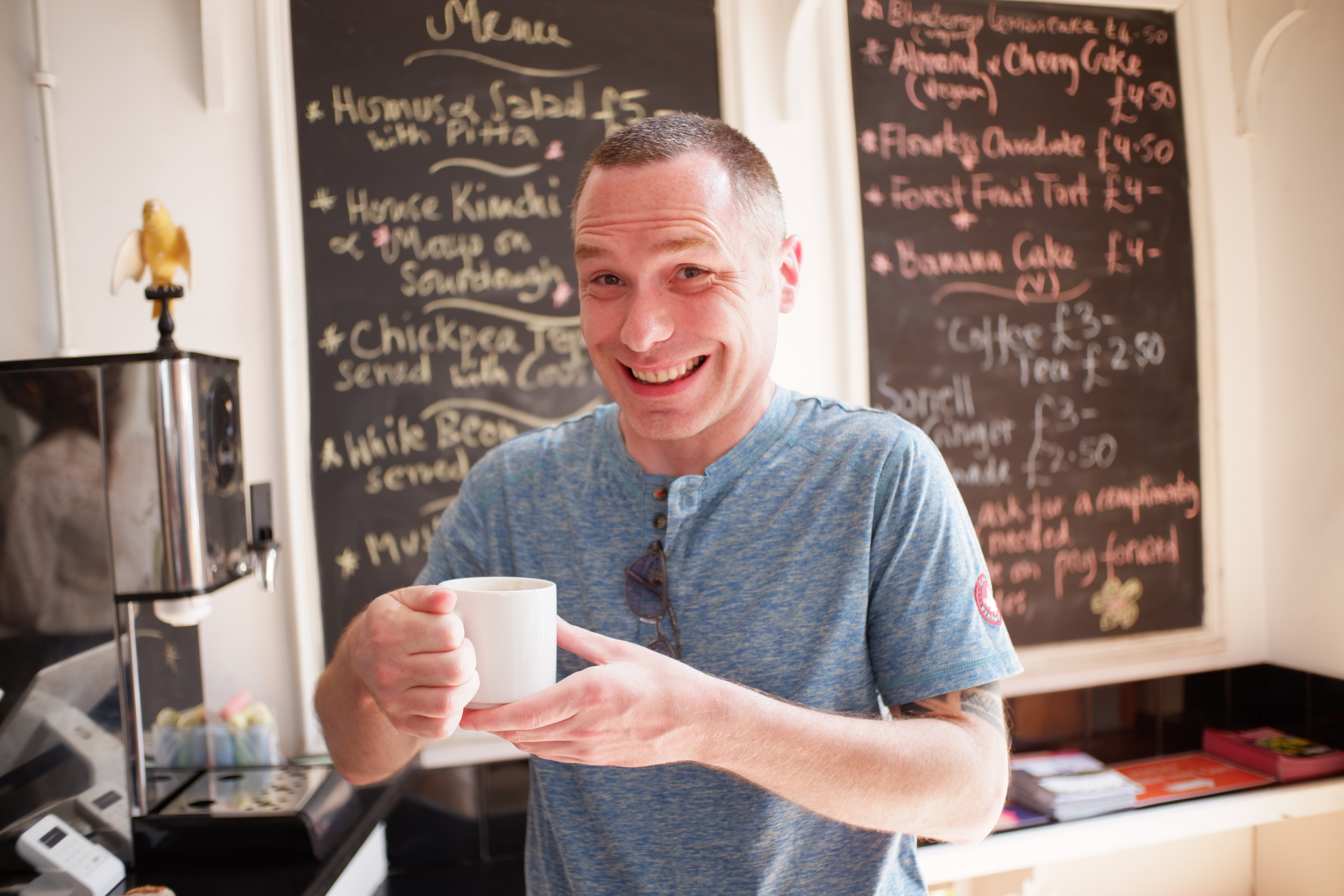 Cheerful individual with a cup in Jamyang Buddhist Centre cafe, ideal for networking events.