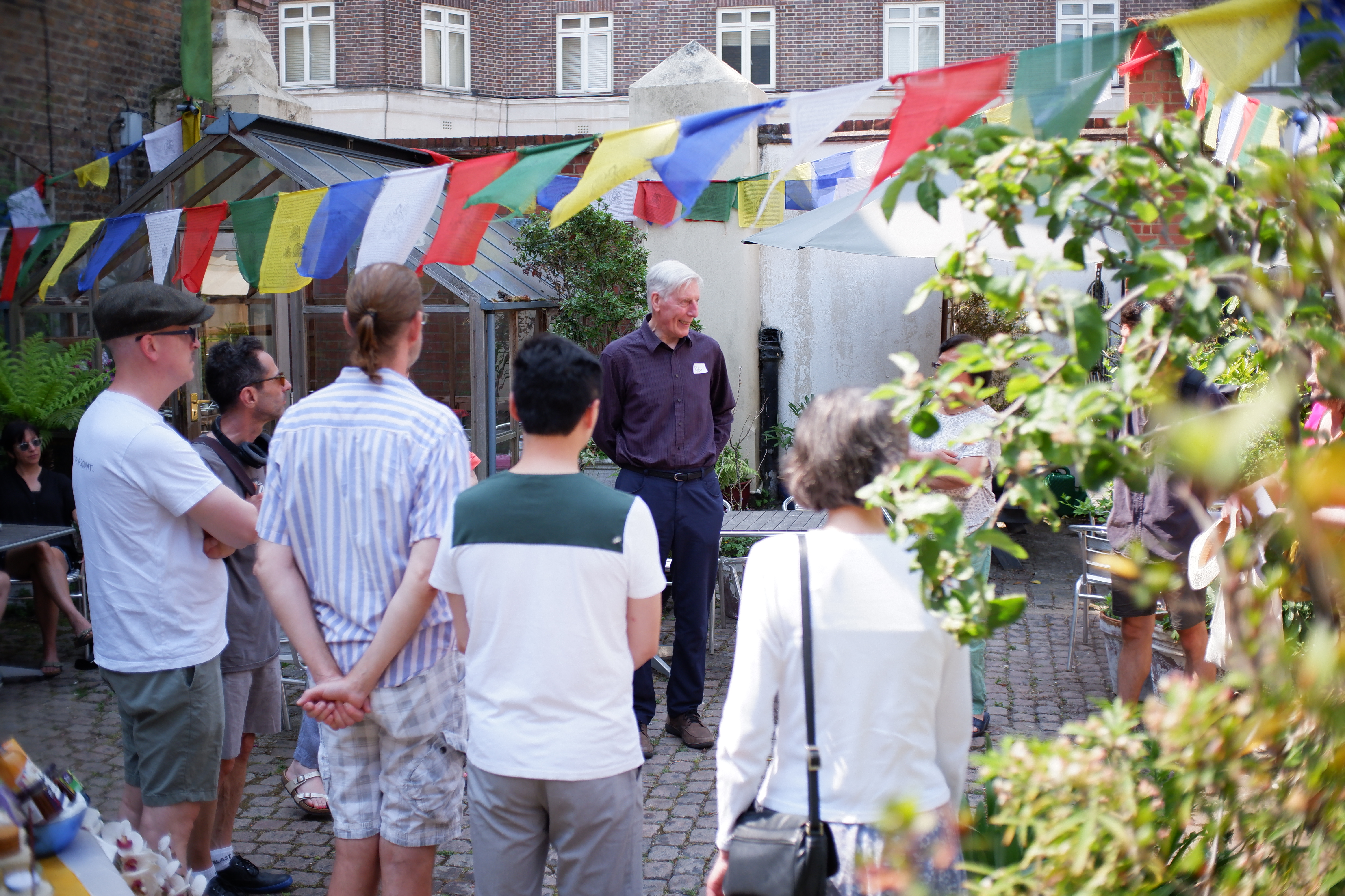 Vibrant outdoor gathering at Jamyang Buddhist Centre with colorful flags for networking event.