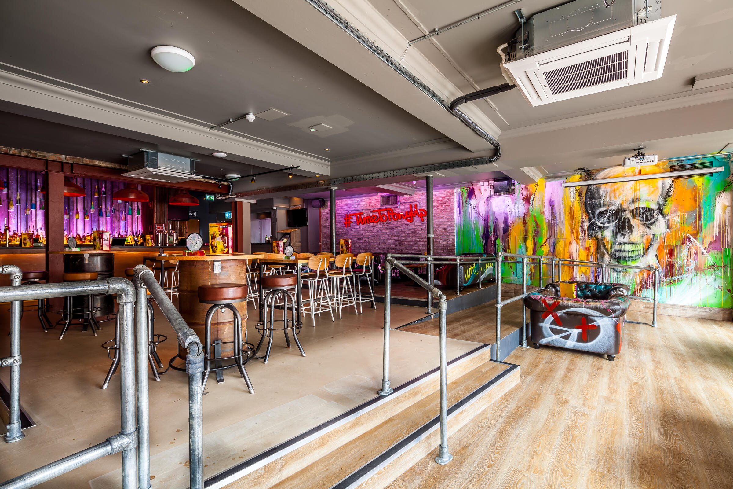 Industrial-chic event venue with split-level bar for networking and corporate receptions.