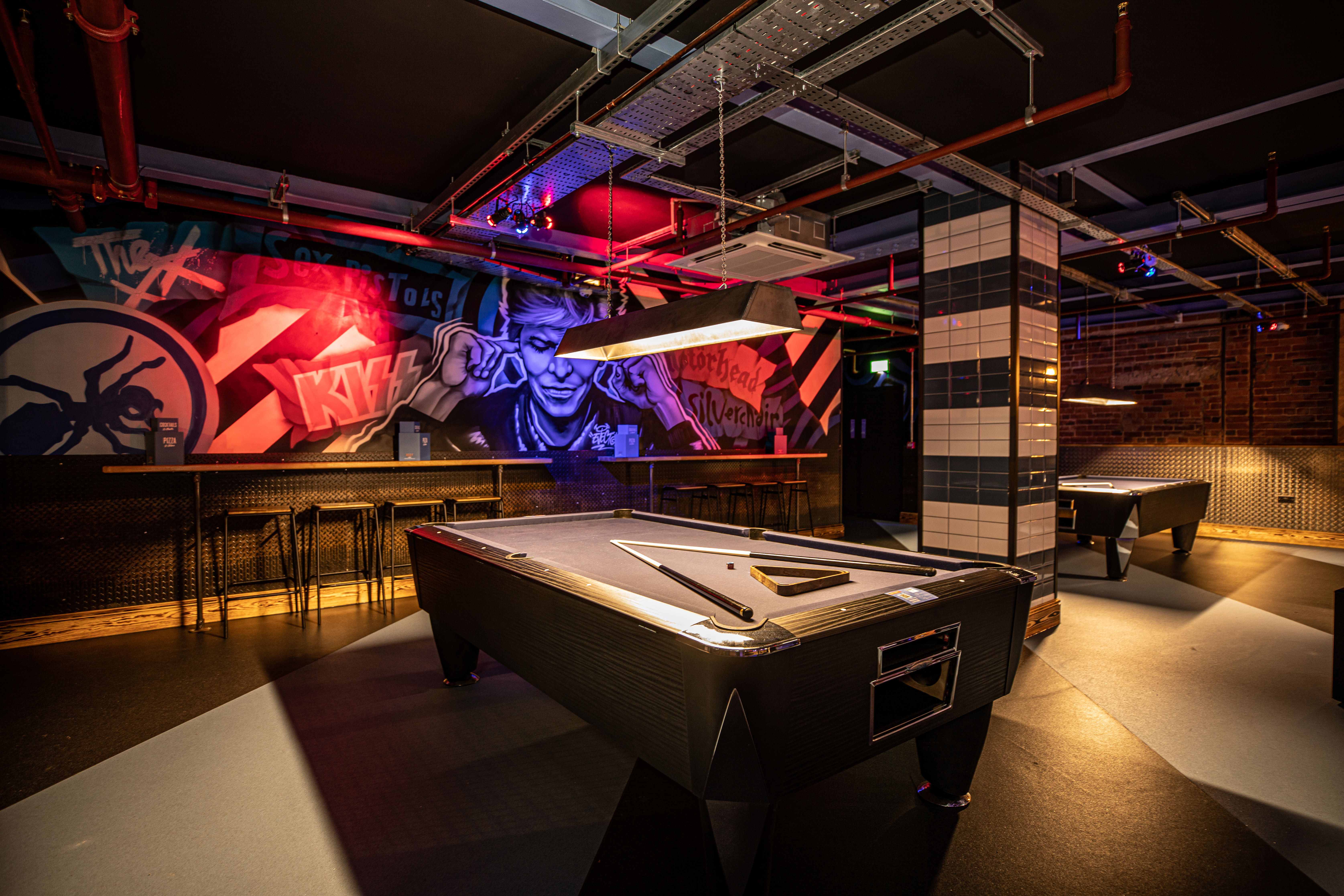 "Stylish gaming venue with pool tables and graffiti art, perfect for networking events."