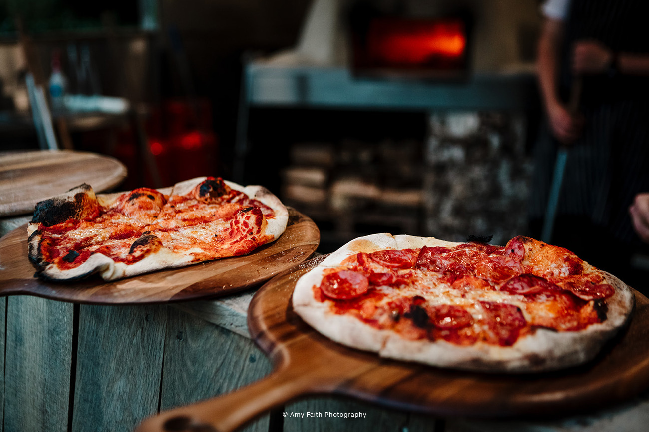 Freshly baked pizzas on rustic boards at The River Room, ideal for events and catering.