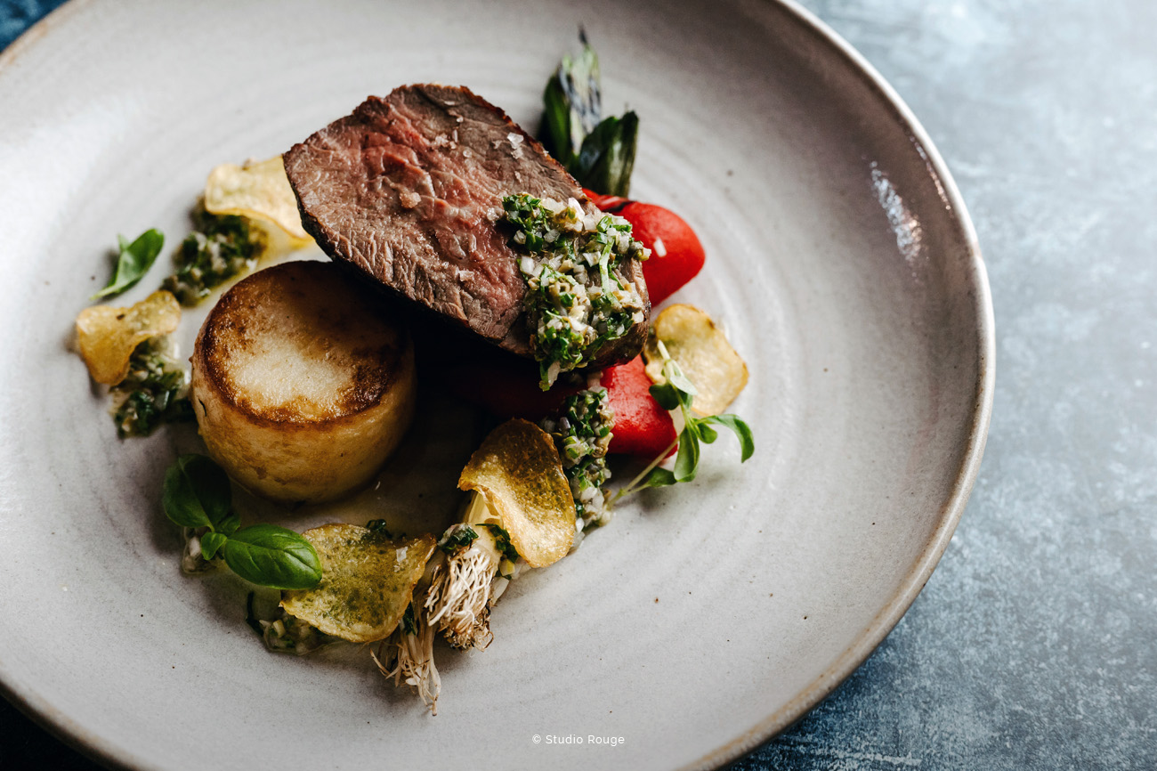 Elegant beef dish with vibrant vegetables at The River Room, perfect for fine dining events.