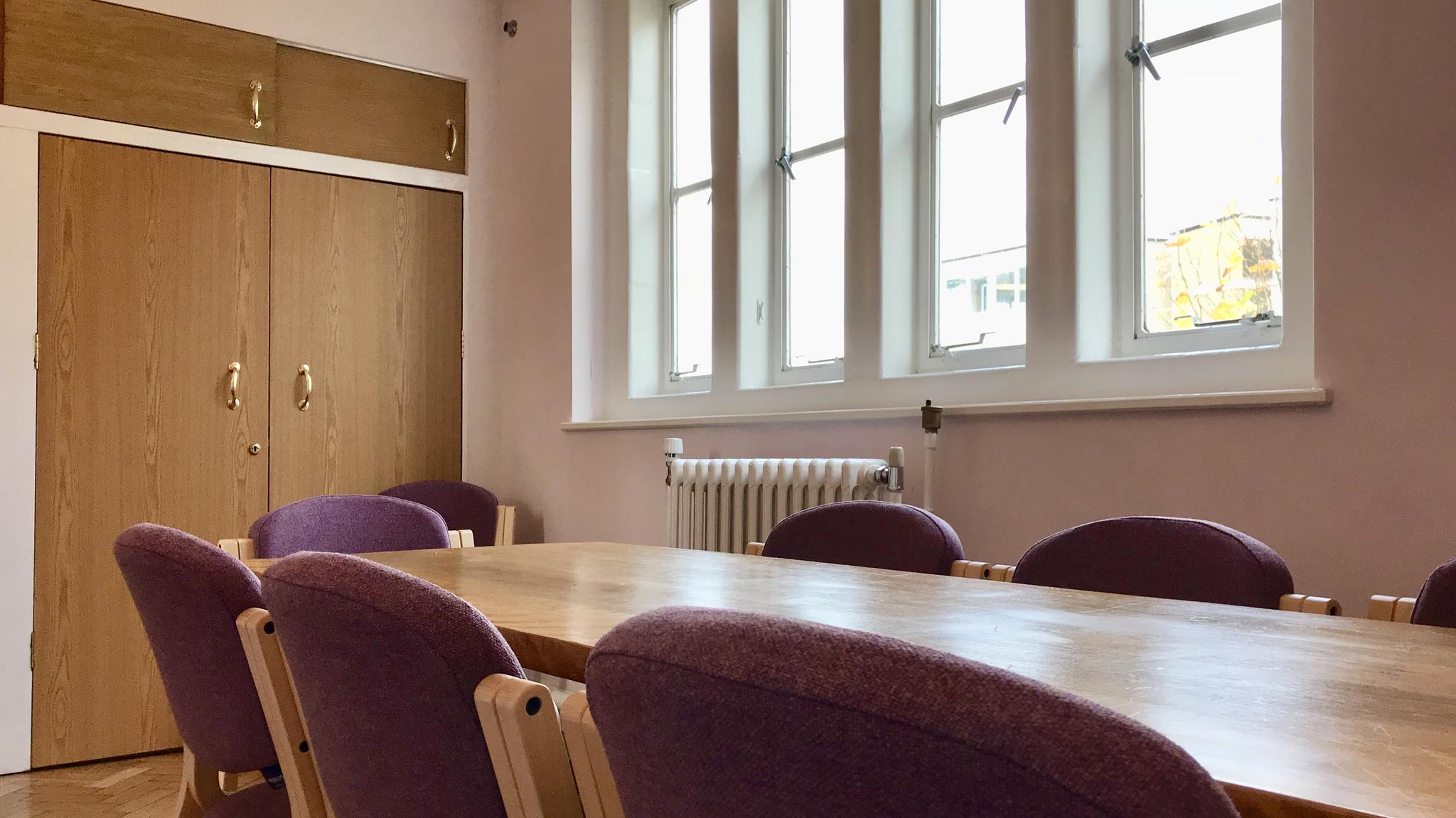 Study room with wooden table and purple chairs, perfect for meetings and brainstorming.