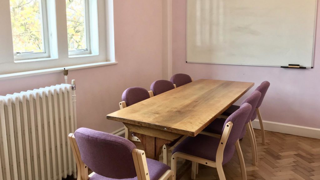 Intimate study room with wooden table and purple chairs for meetings and brainstorming.