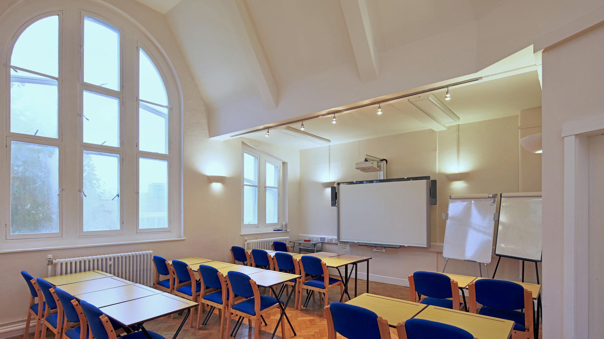 Well-lit workshop space in Rudolf Steiner House with tables, chairs, and projector.