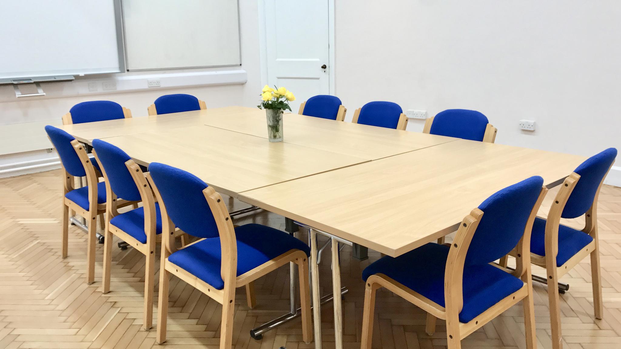 Conference room with large table and blue chairs, perfect for meetings and workshops.