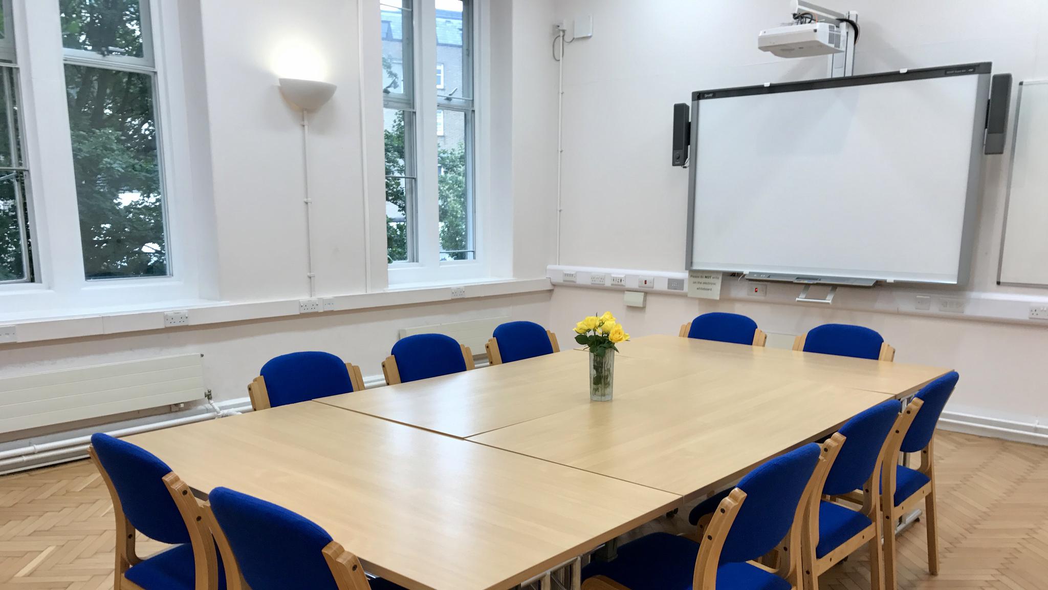 Conference room with large table and blue chairs, perfect for workshops and presentations.