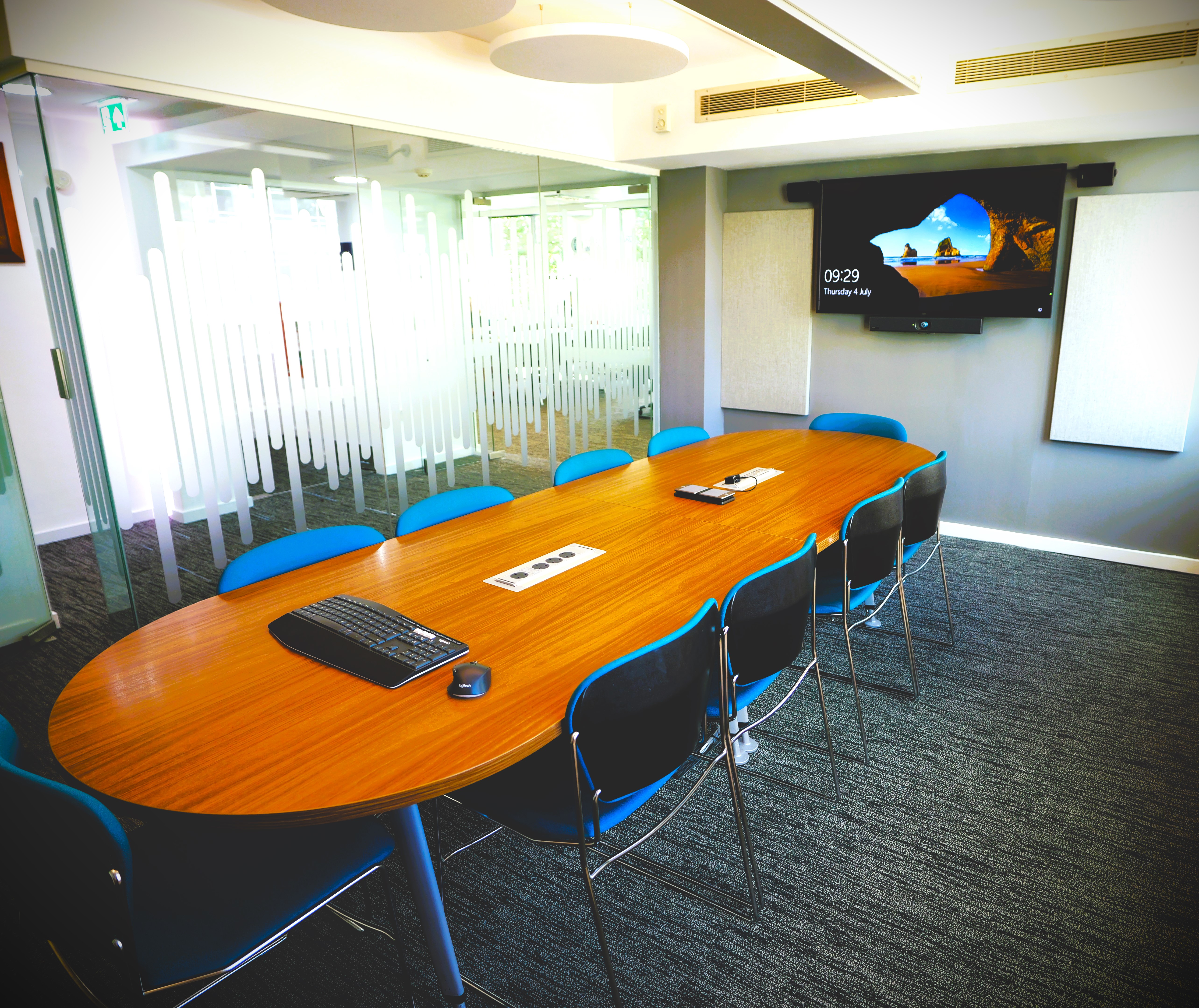Modern meeting room with oval table and blue chairs for corporate events.