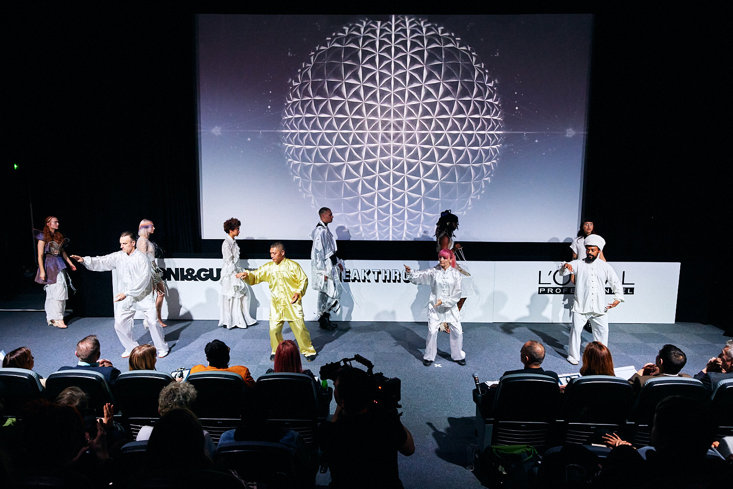 Dynamic stage performance at Riverside Studios with vibrant costumes and geometric backdrop.