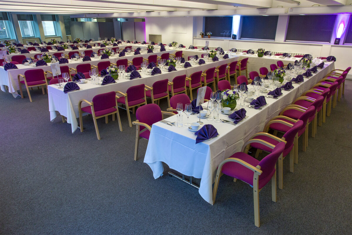 Elegant banquet setup with white tablecloths and purple napkins at Churchill House event.