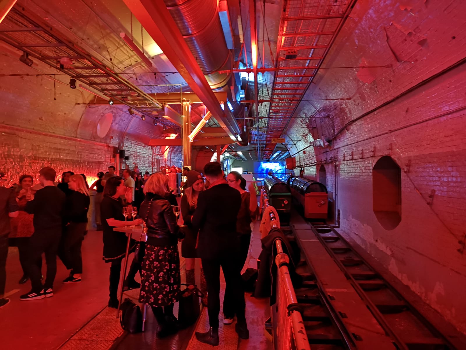 Vibrant party at Mail Rail, featuring red lighting and industrial decor for networking events.