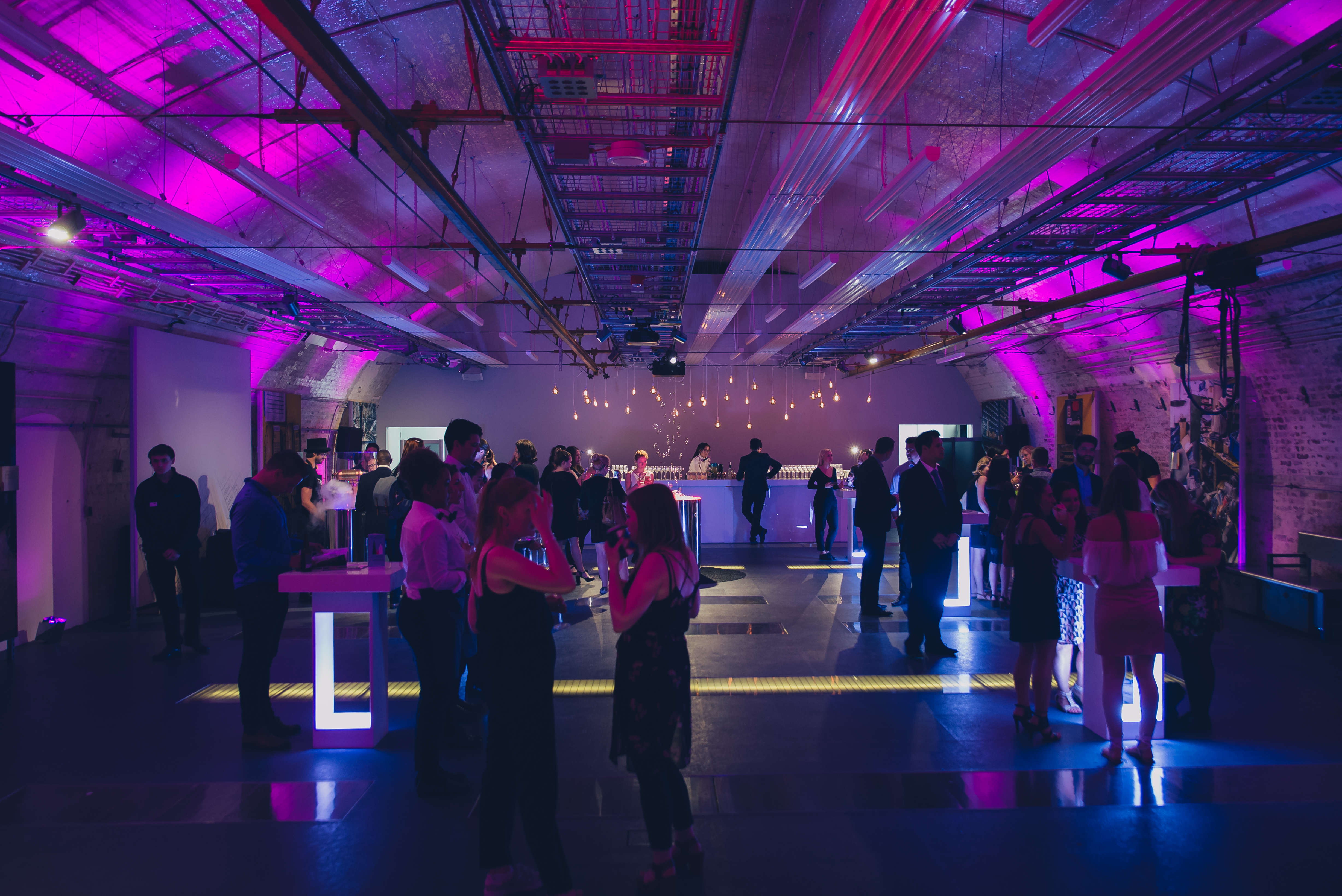 Vibrant networking event at The Postal Museum with purple lighting and modern tables.