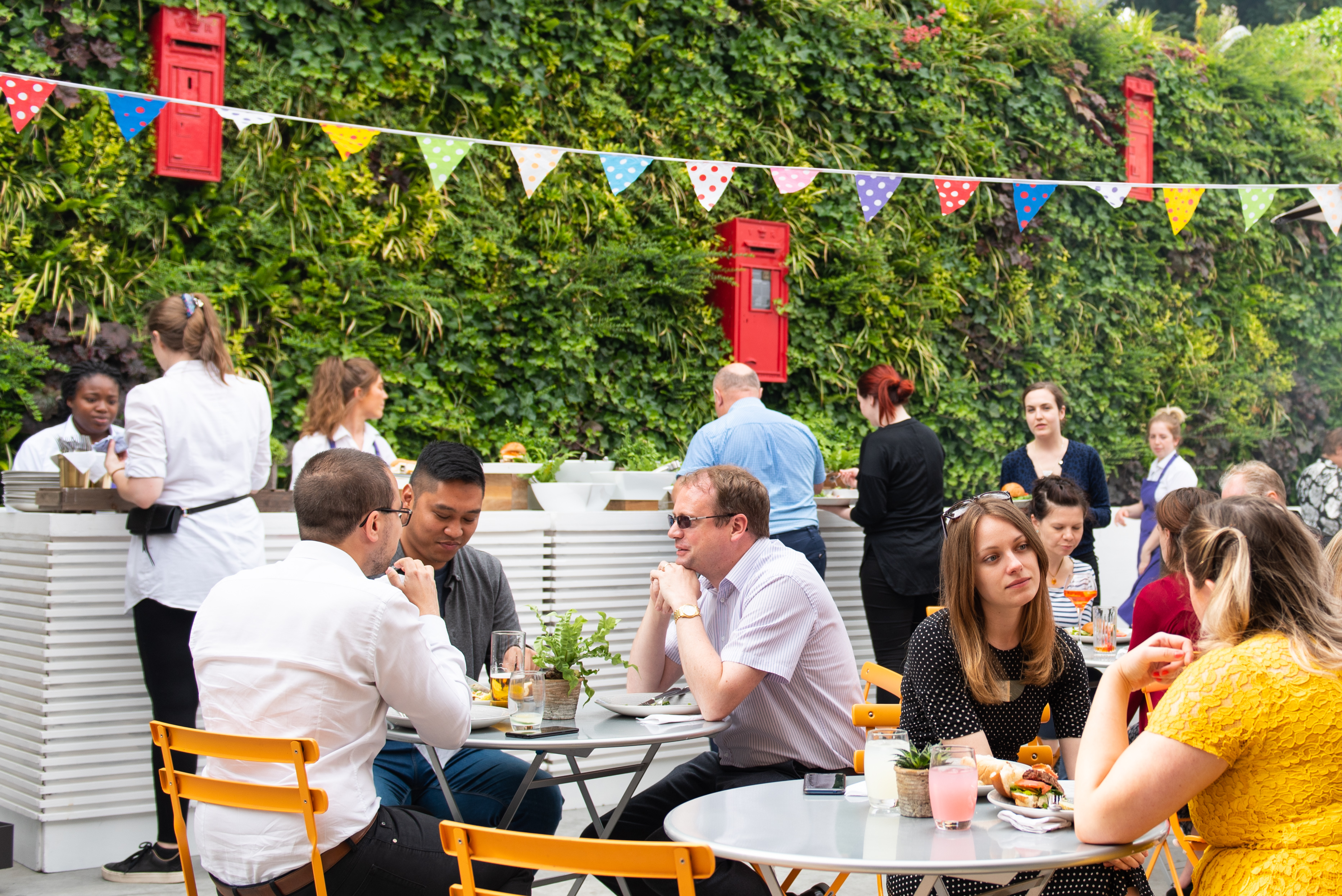 Summer party in The Postal Museum courtyard with colorful bunting and guests dining.