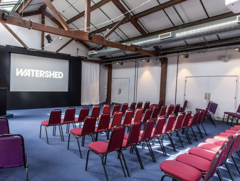 Versatile event space with stage and screen, perfect for conferences and workshops.