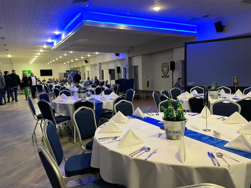 Hall of Fame Lounge banquet setup with blue lighting for corporate events and presentations.