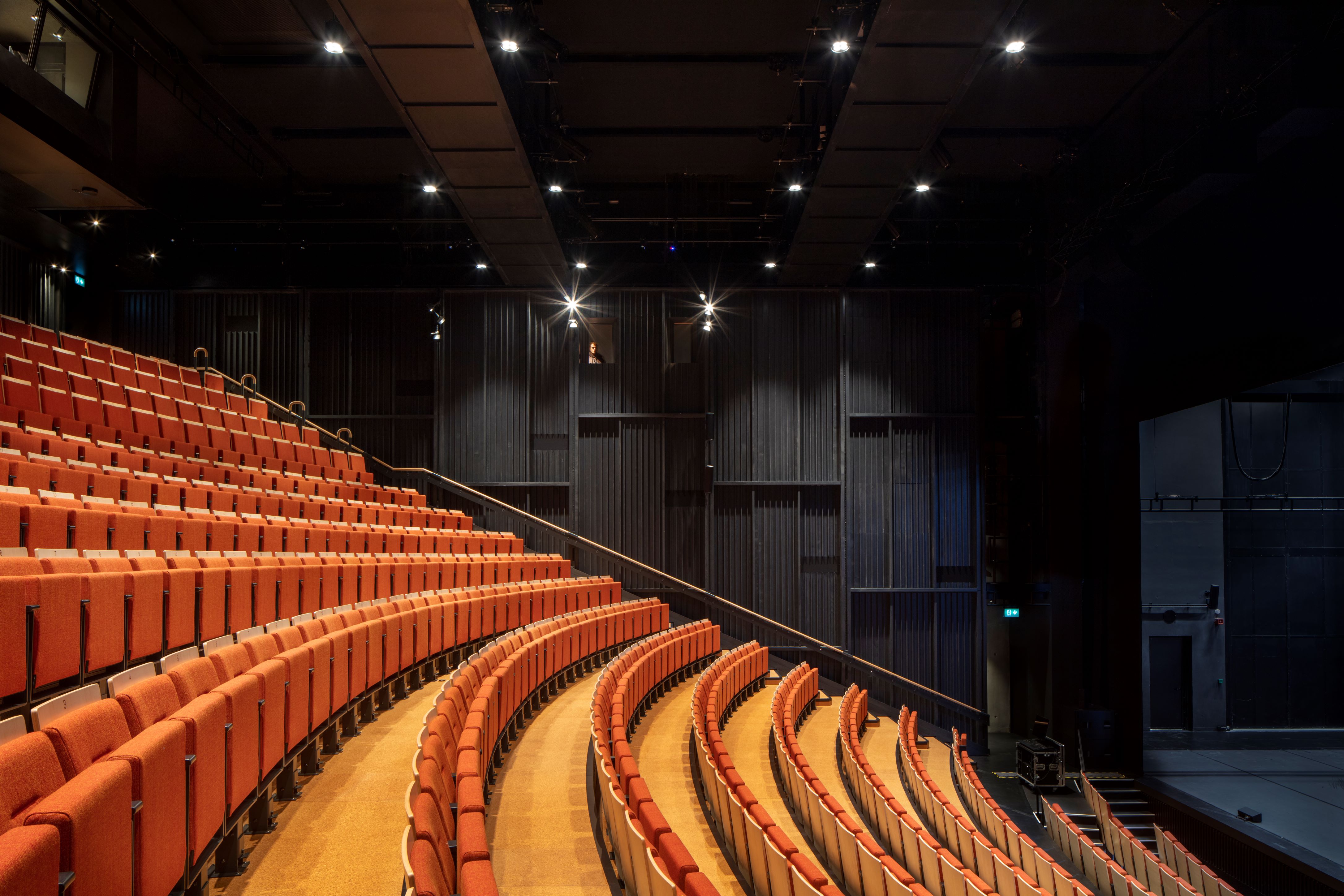 Modern auditorium with tiered orange seating for dynamic performances and events.
