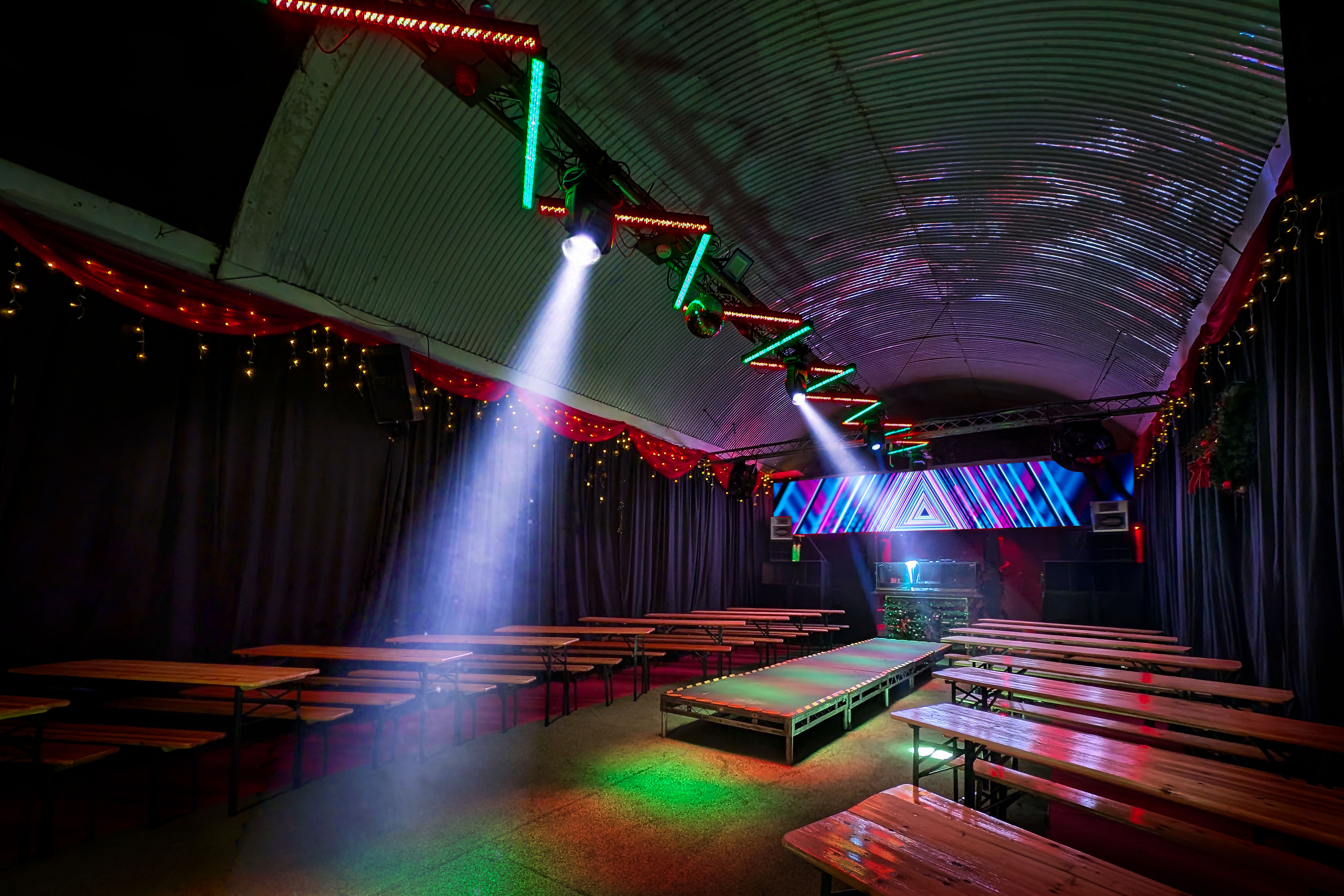 Industrial-chic event venue with arched ceiling and truss lighting for experiential gala.