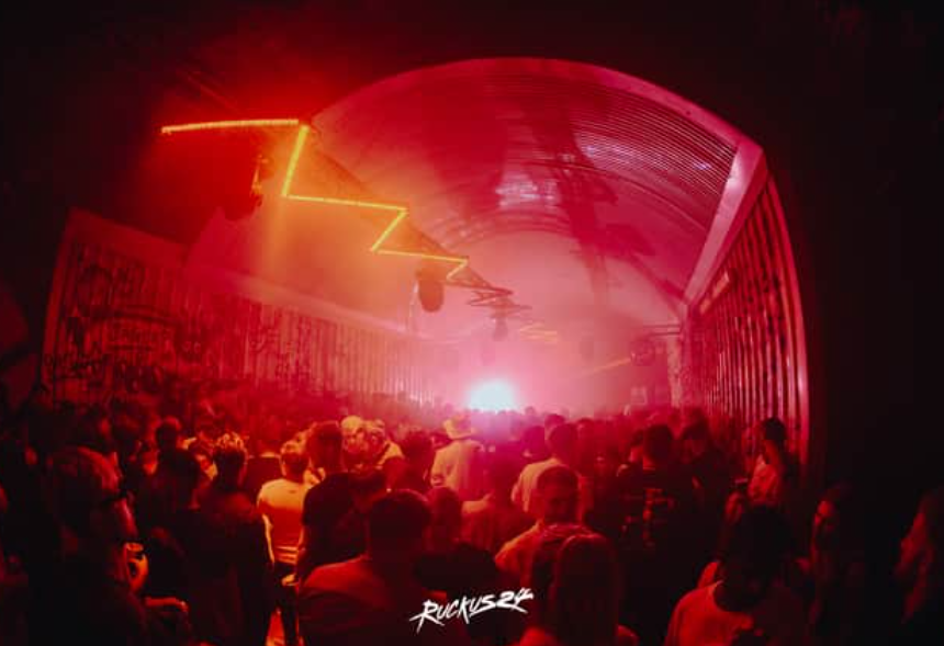 Industrial-chic event venue with red lighting and neon sign for nightlife and private parties.