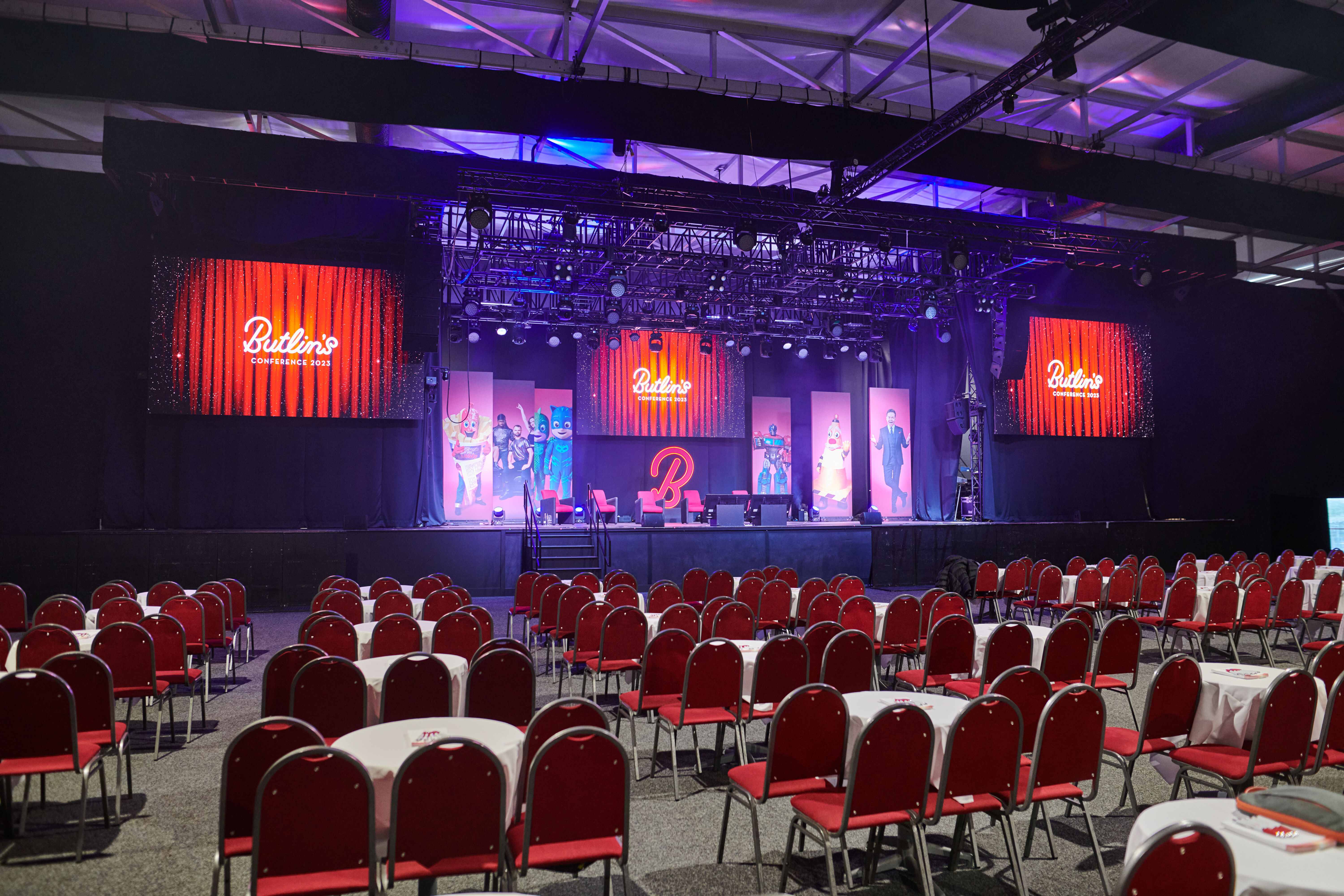 Event space at Butlin's Bognor Regis with vibrant stage and red seating for presentations.