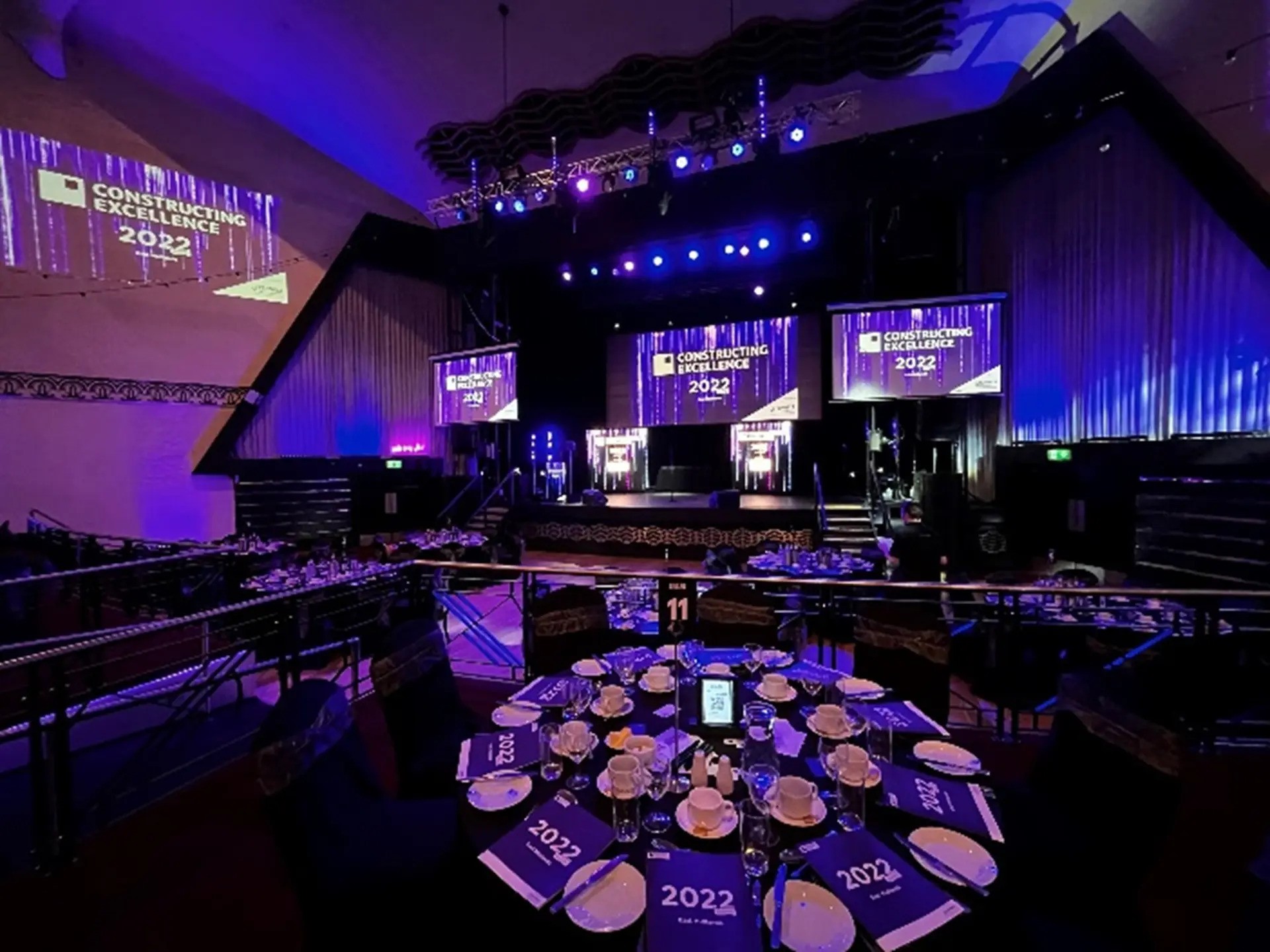 Elegant event space for Construction Excellence 2022 with set tables and stage.